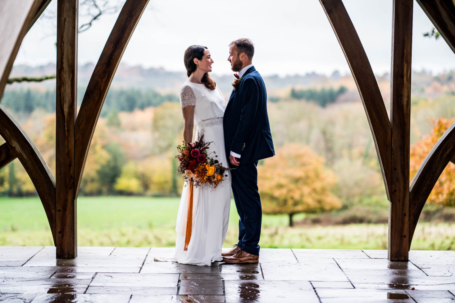 couple looking at each other with backdrop of sussex countryside at highley manor behind them