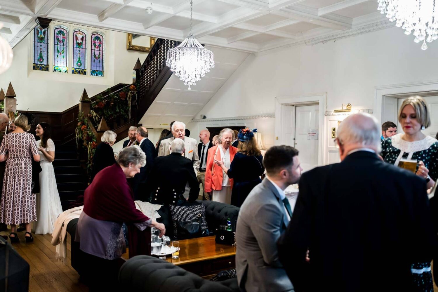 zoomed out view of main reception room at highley manor where guests are drinking