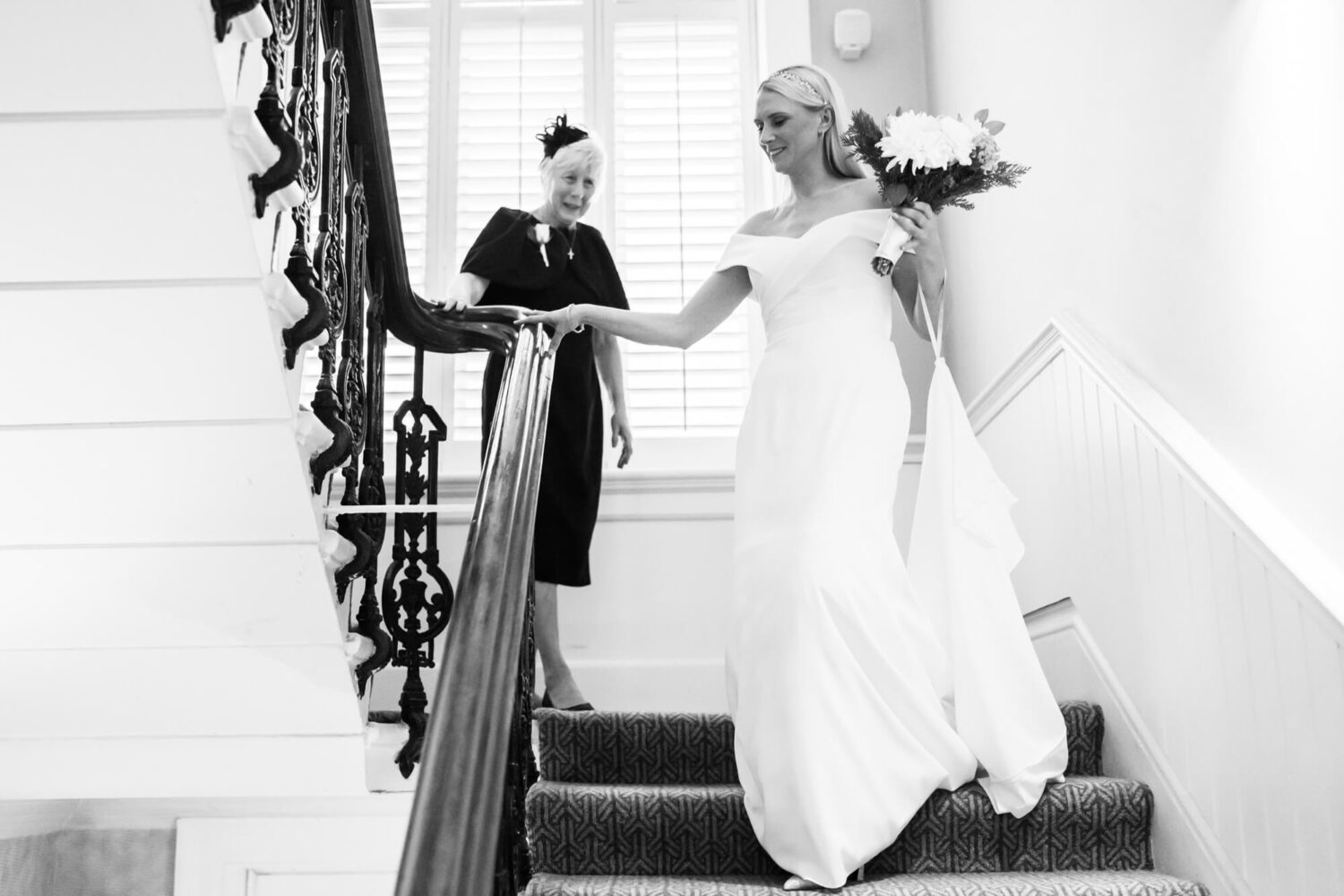 bride walking down hotel stairs with mother in background