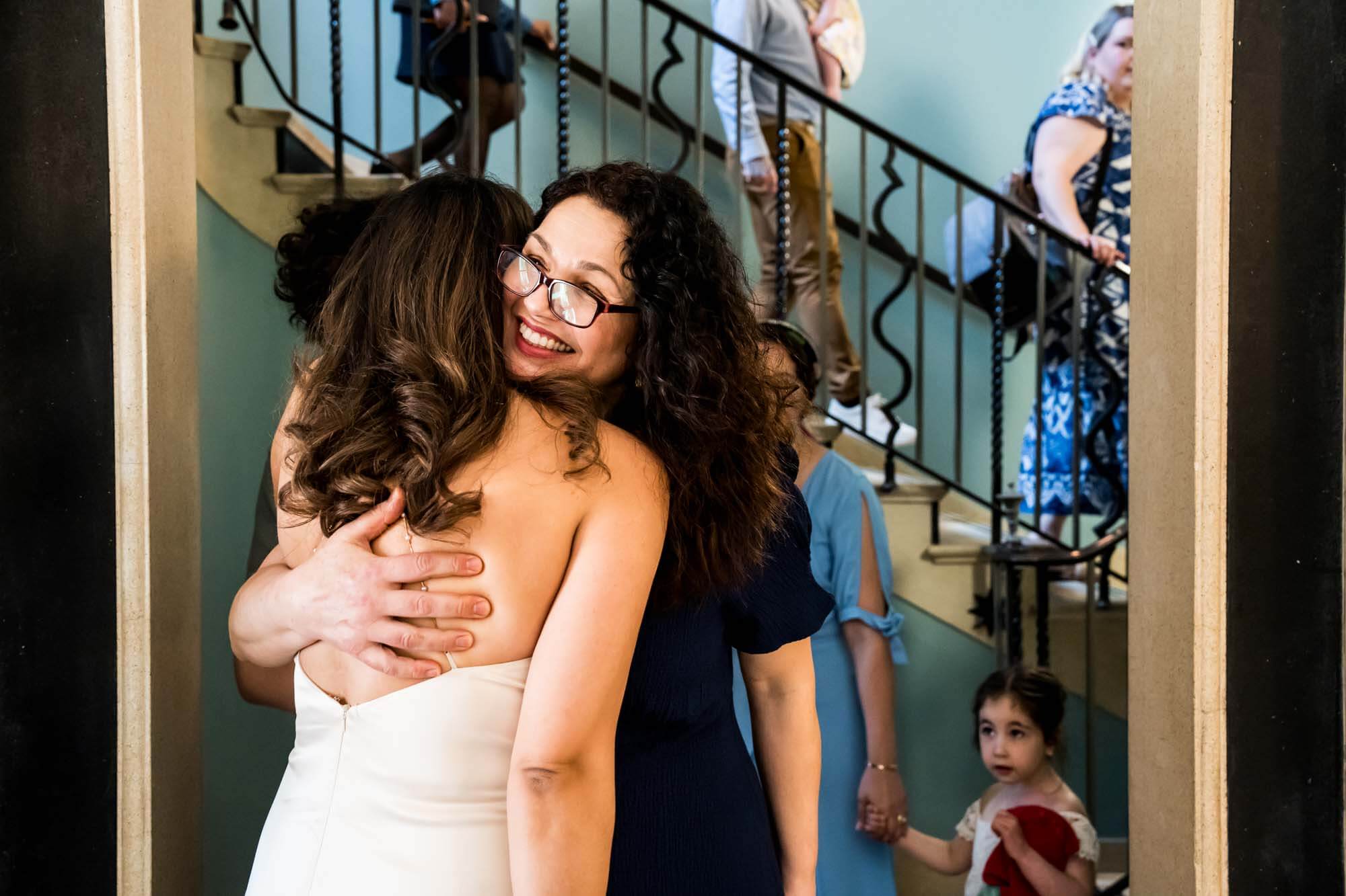 mother hugging bride people walking down stairs in background london wedding