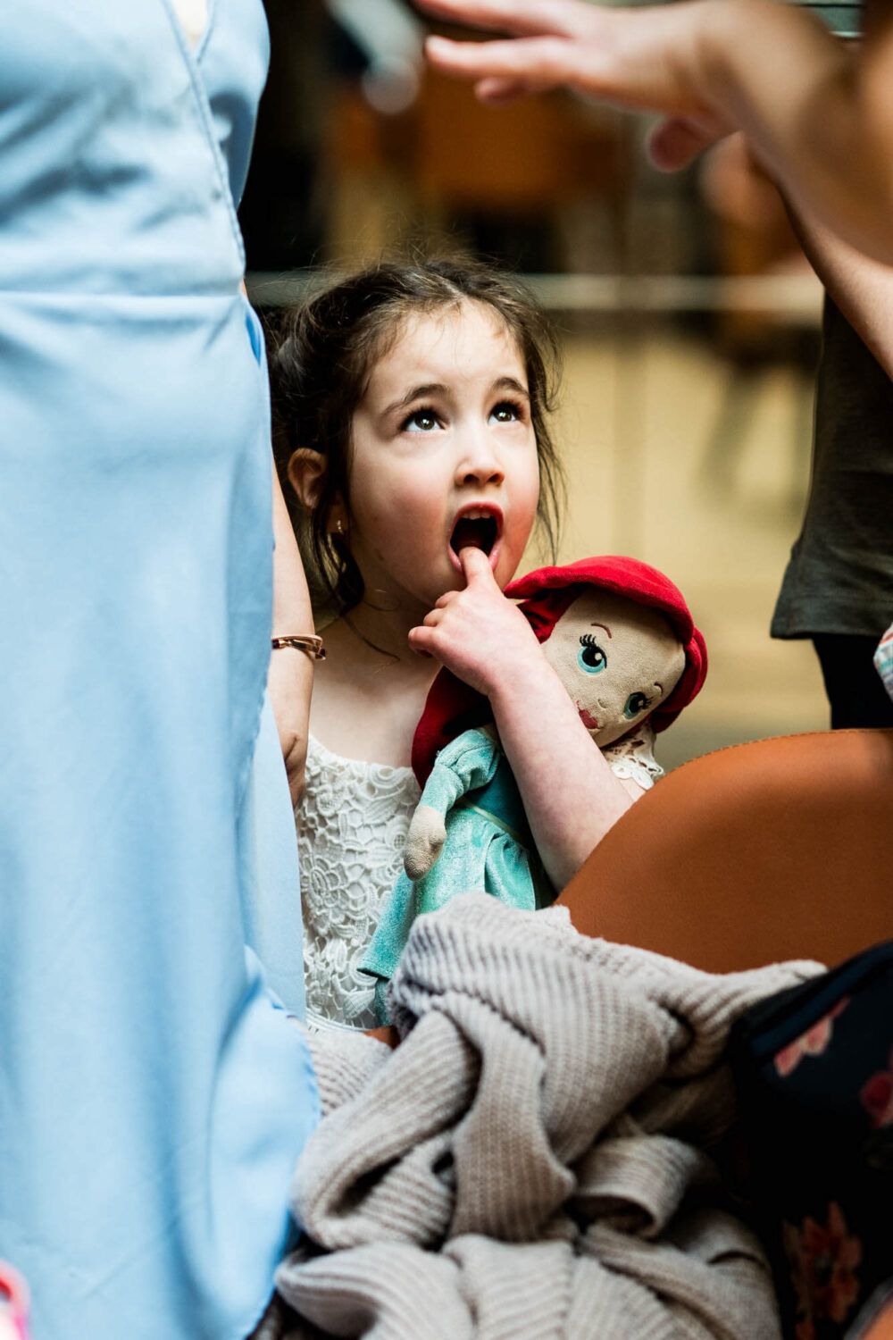 girl holding doll looking up at parent london wedding