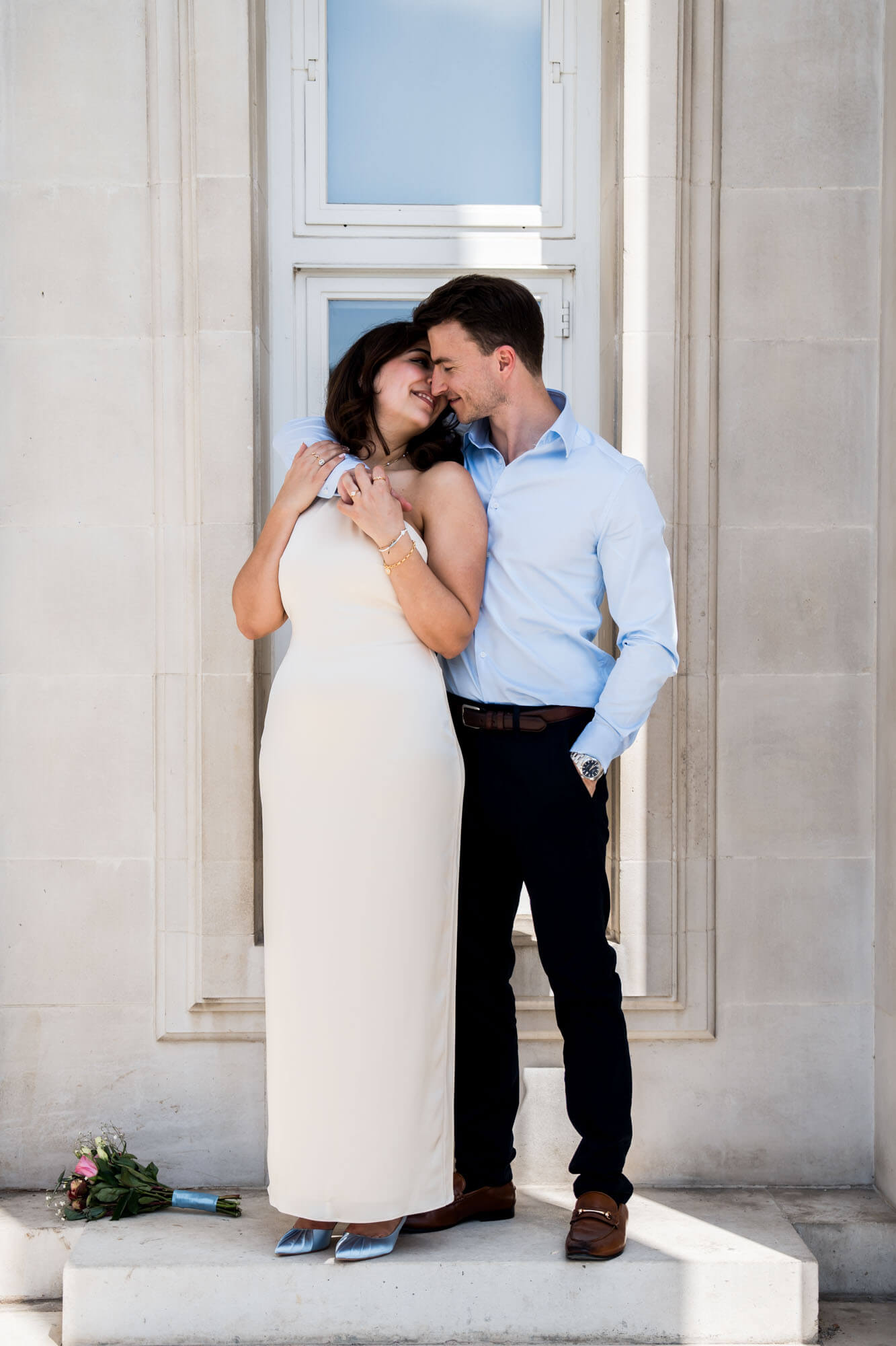 groom arms around bride her hands holding his looking back at each other london wedding
