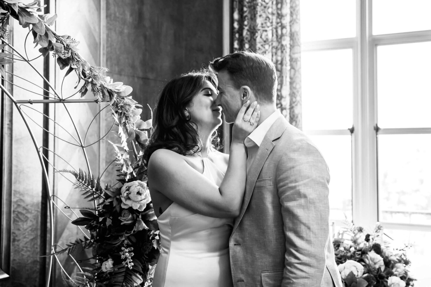 bride holding hand upto groom's face to kiss for the first time london wedding