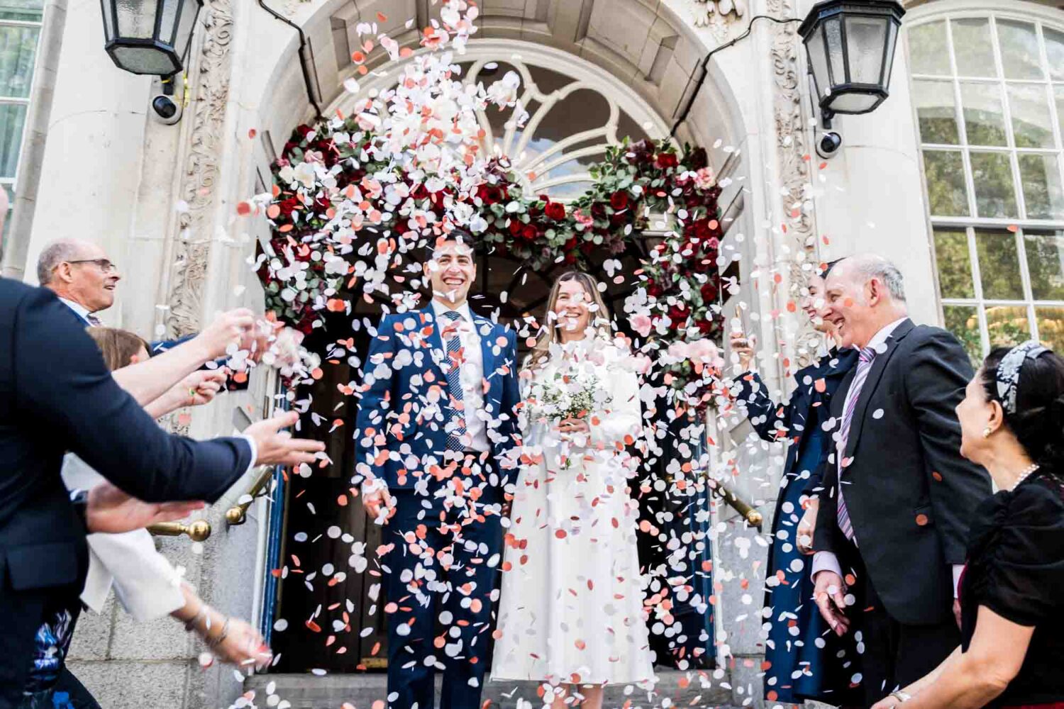 couple walking out in confetti shower london wedding