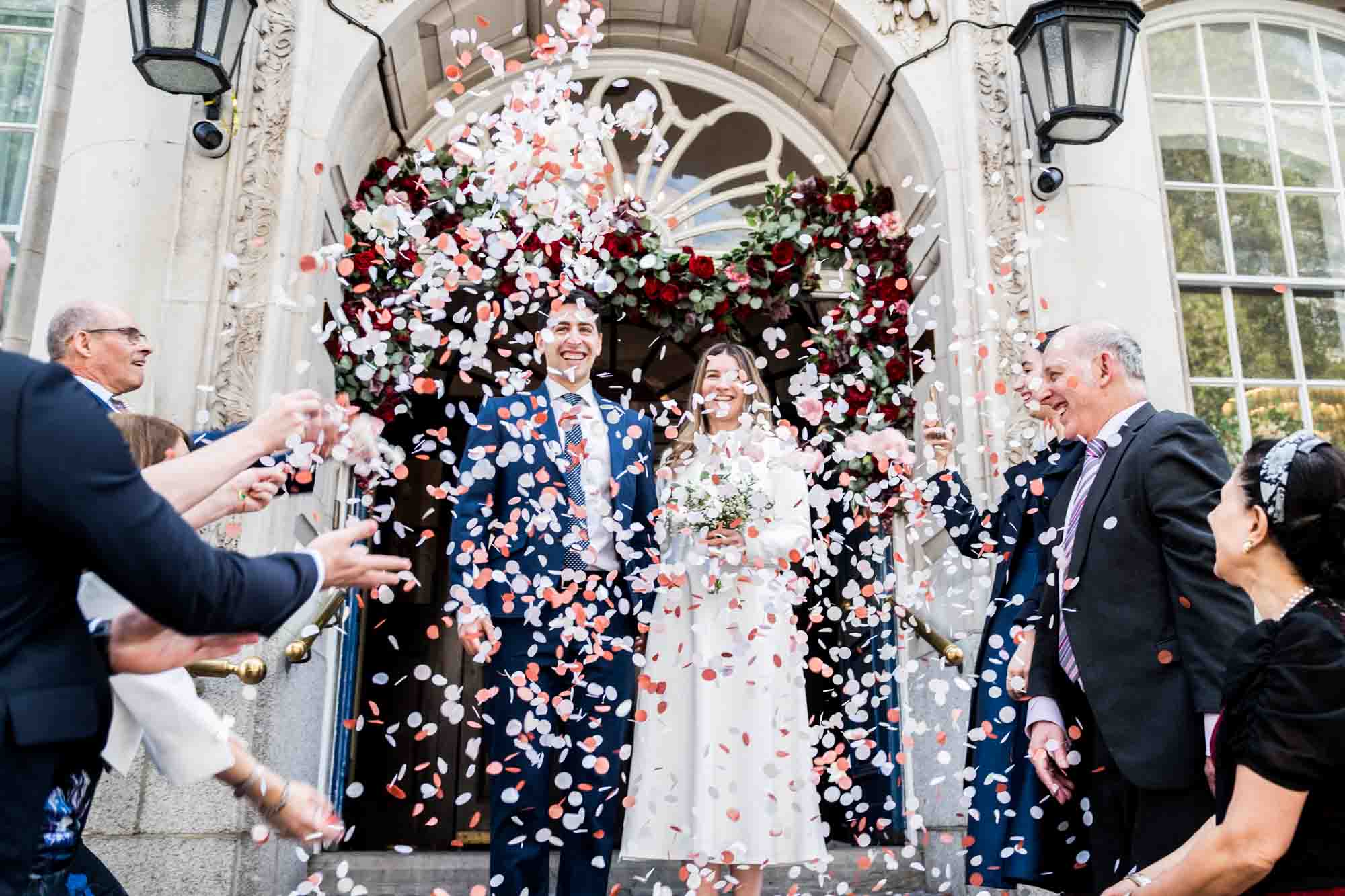 couple walking out in confetti shower london wedding