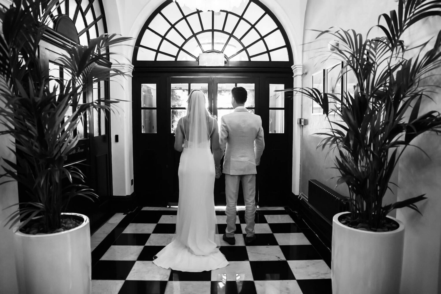 bride and groom behind door reading to walk out onto famous steps chelsea town hall