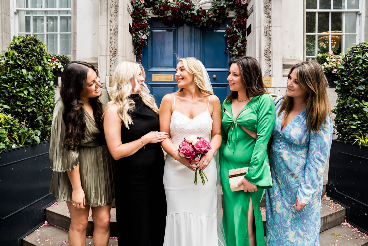 bride and friends on steps smiling at each other london wedding