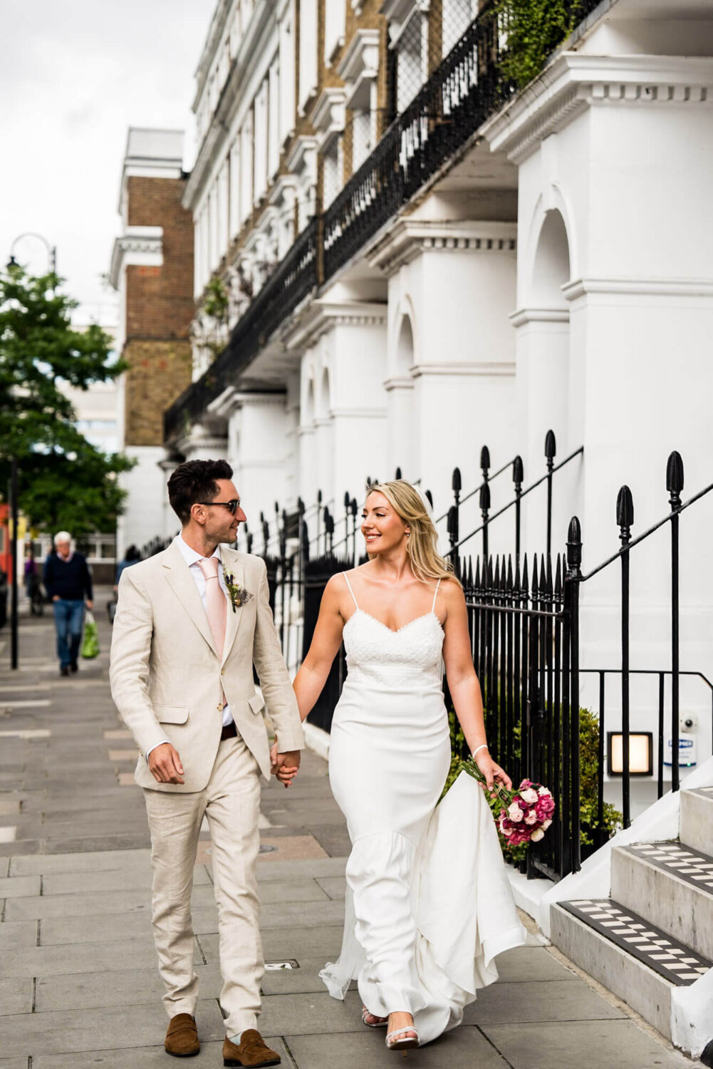 bride and groom walking down road looking at each other holding hands london wedding