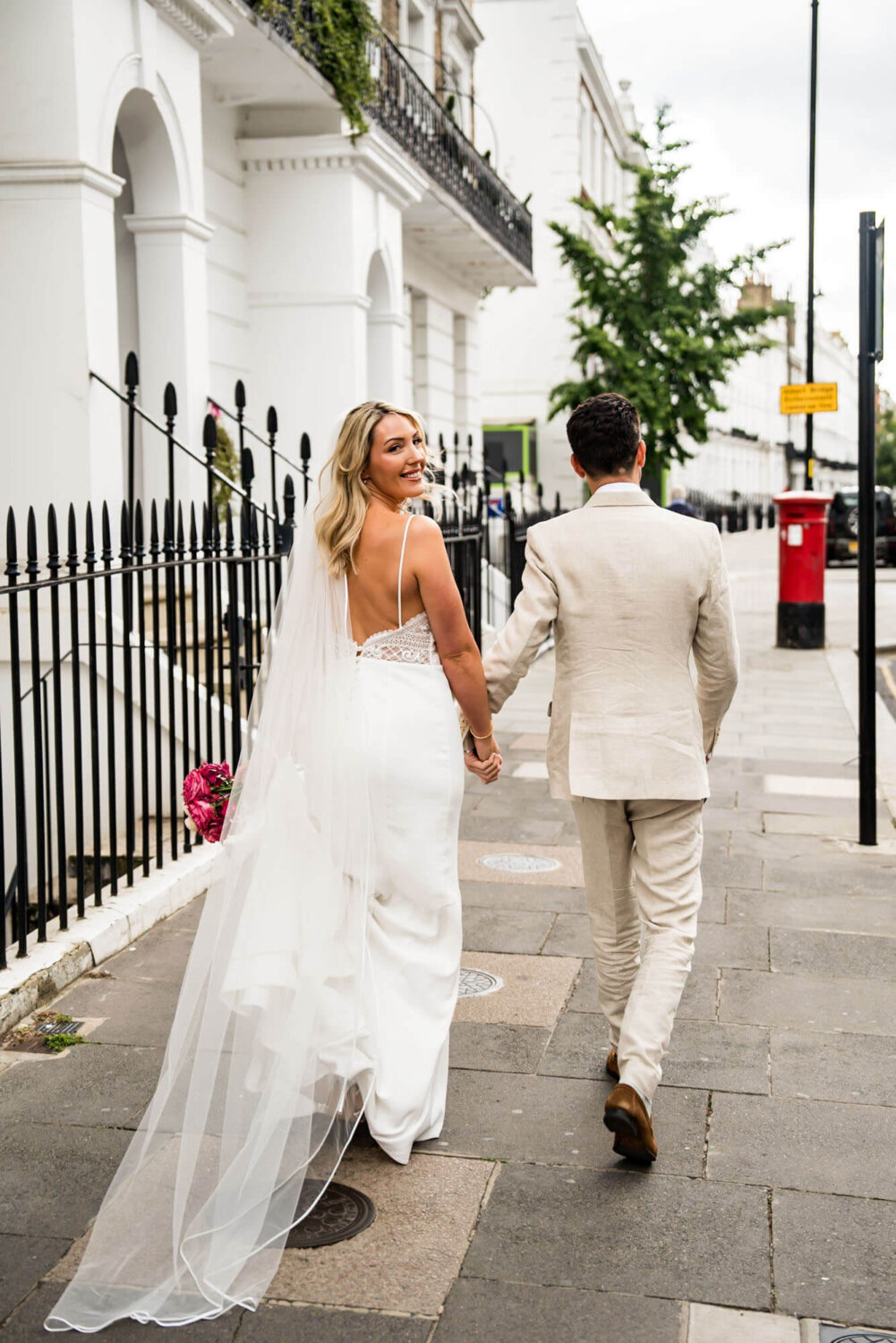bride looking over shoulder as she walks down street london wedding