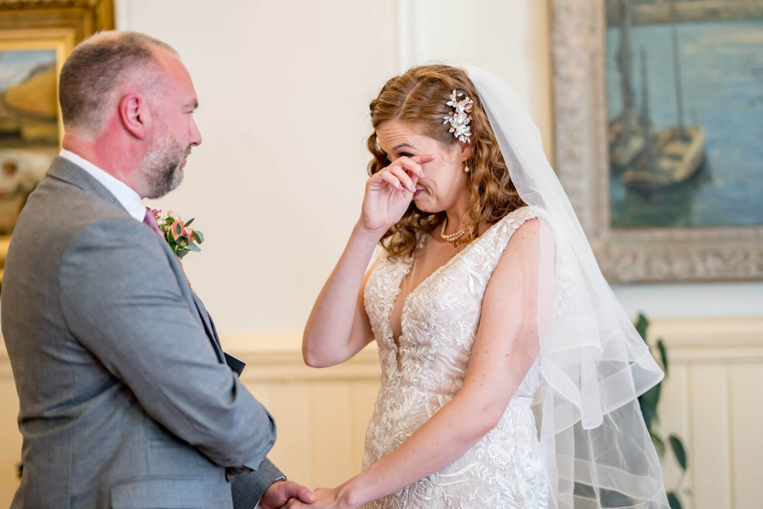 bride wiping away a tear holding grooms hand