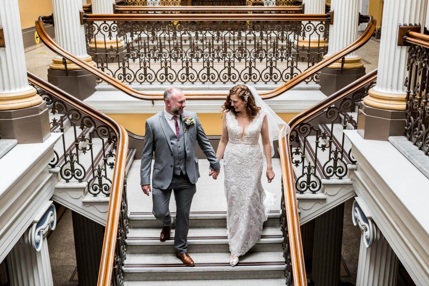 bride and groom walking down steps in town hall