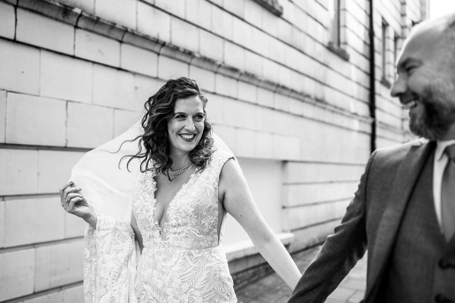 bride holding onto veil smiling looking at husband in brighton wedding