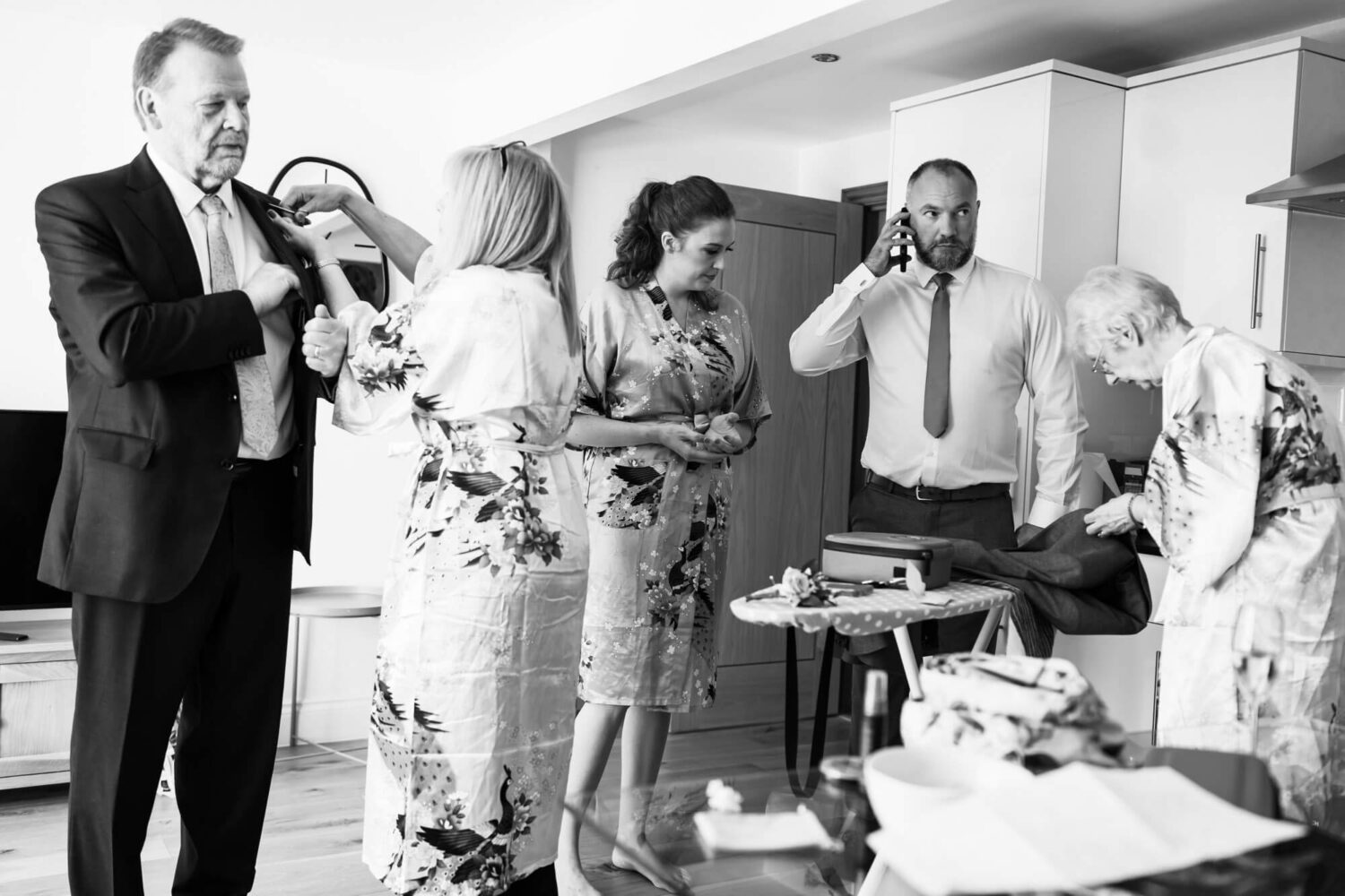 busy getting ready scene with ironing people on phones button hole being put on brighton wedding