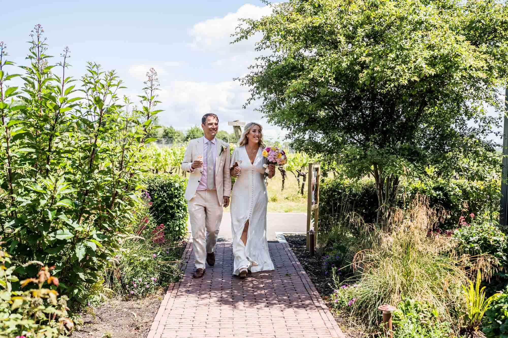 Bride and groom walking down stone path.