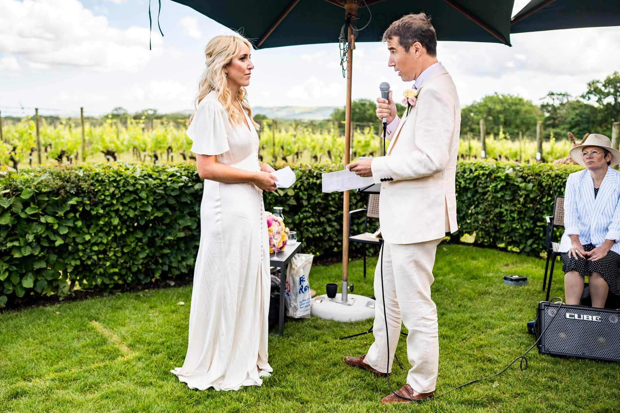 Groom making speech and looking at bride.
