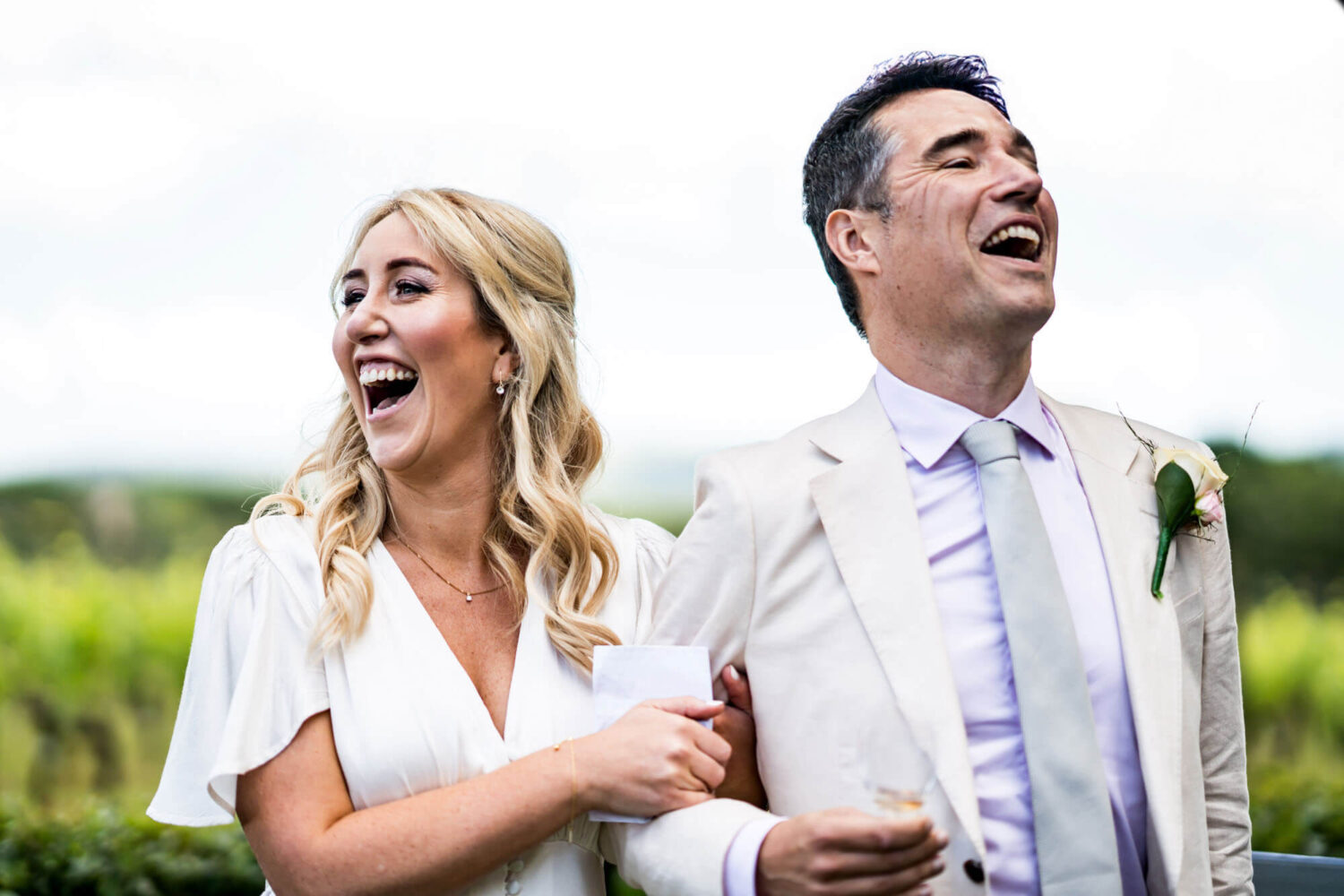 Bride and groom laugh, arm in arm.