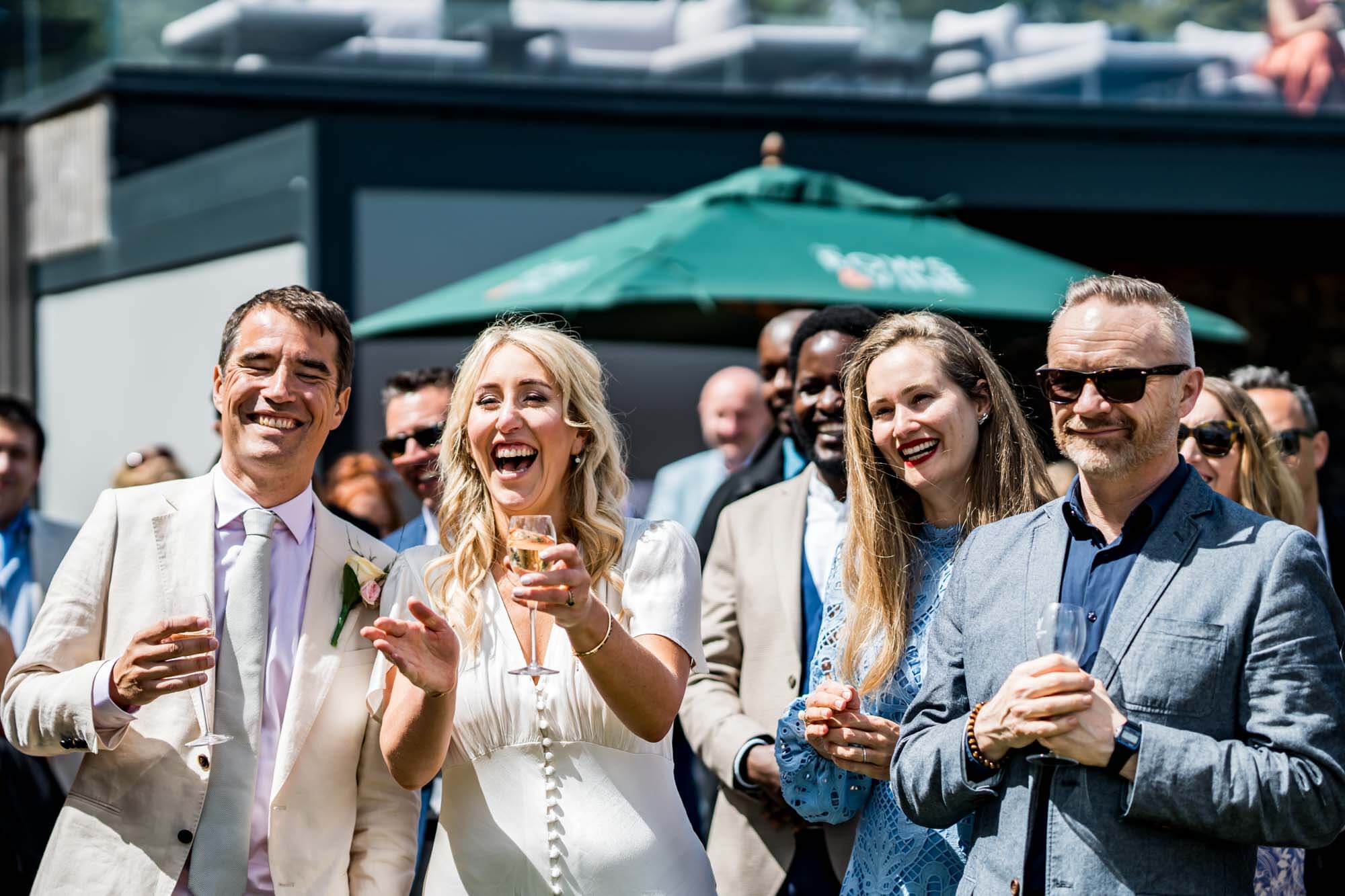 Bride, groom and guests laughing.