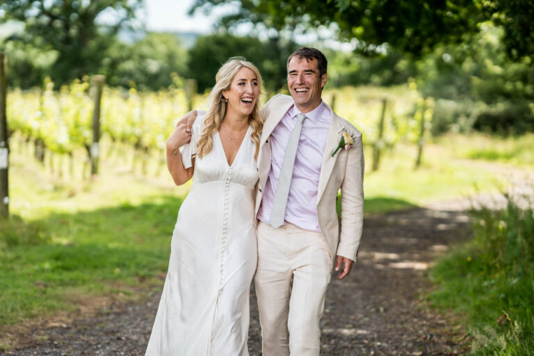 Bride and groom laughing and walking.