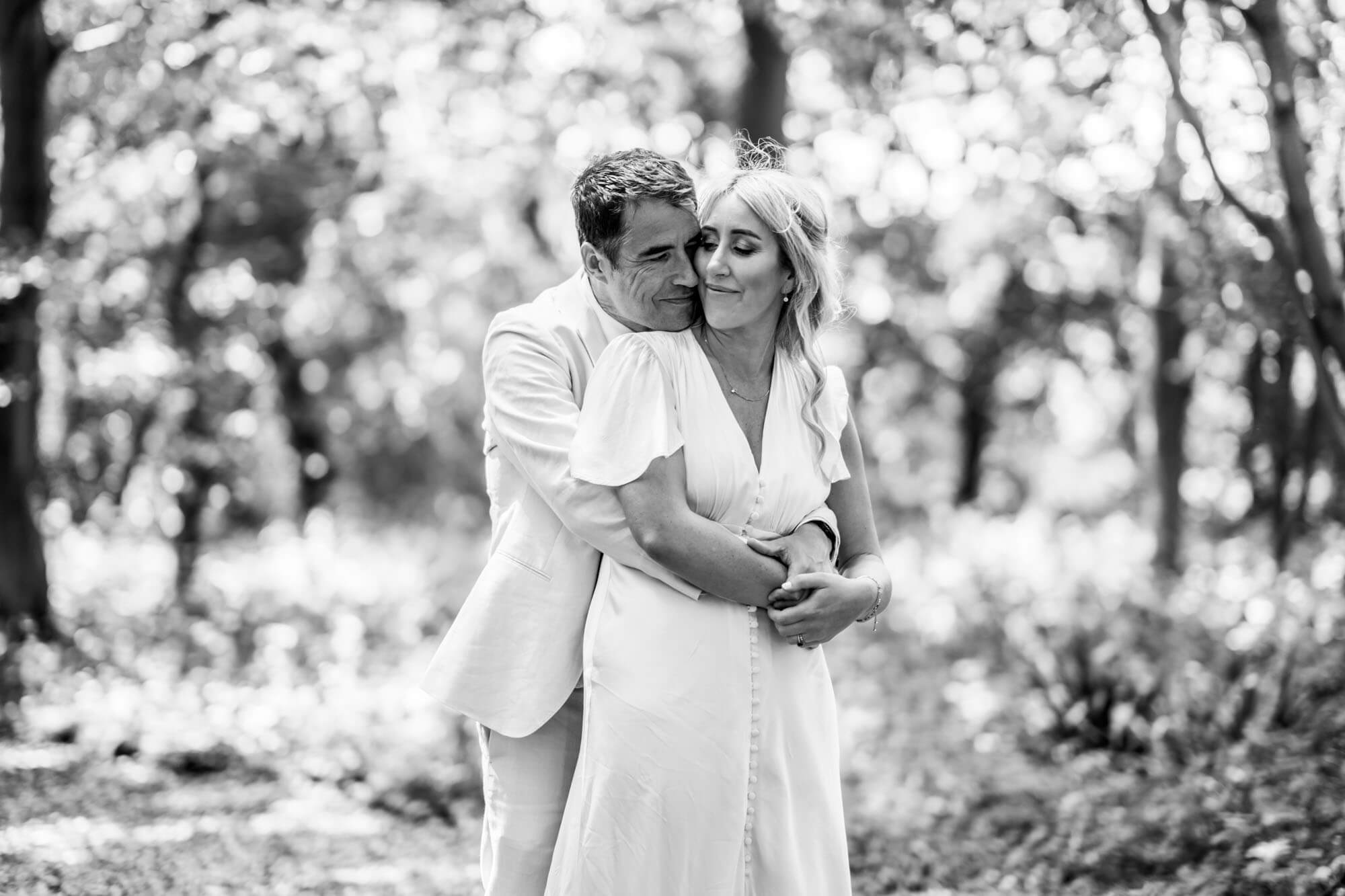 Groom hugging bride from behind - B&W.