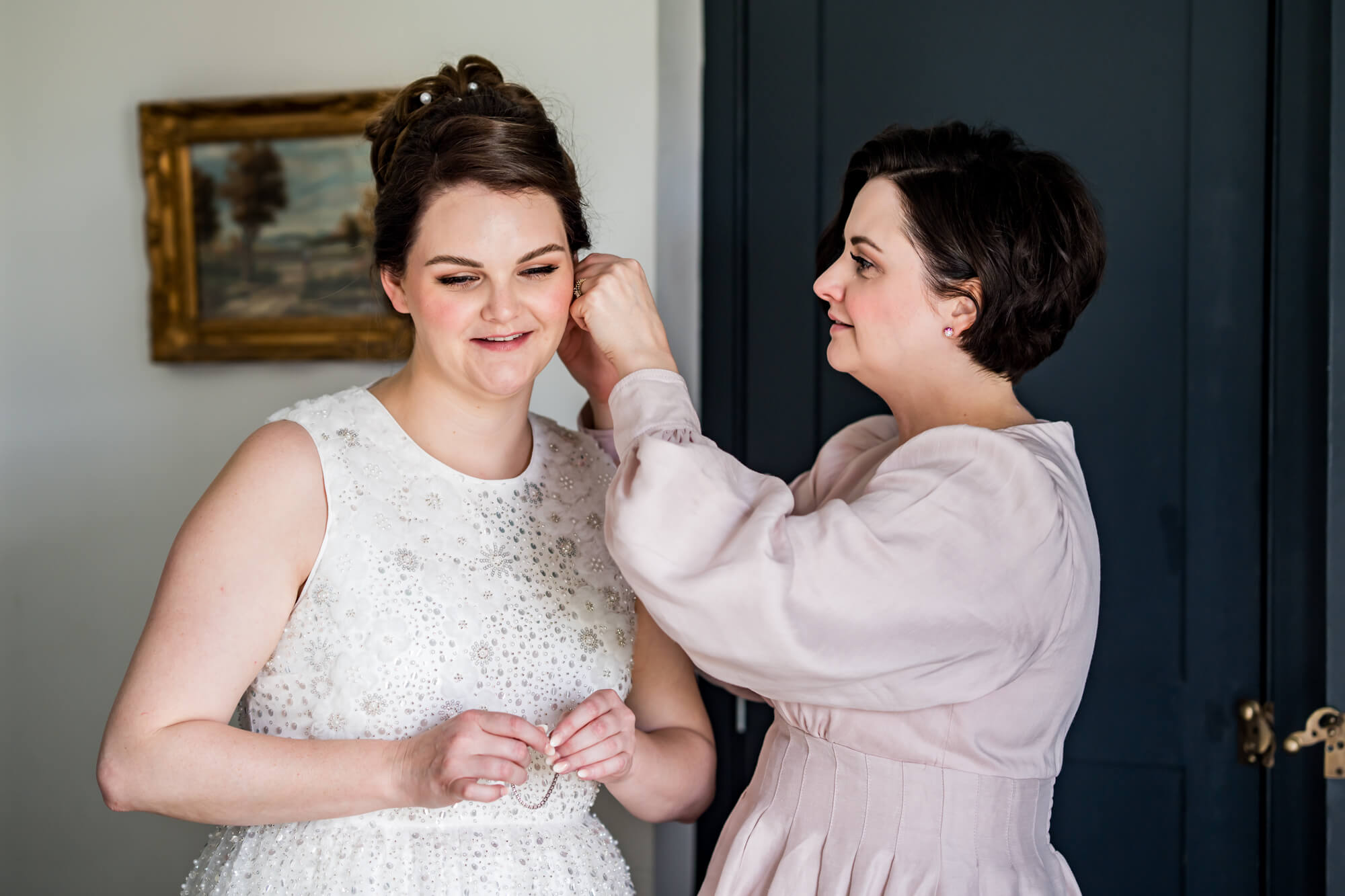 Woman attaching earrings to bride.