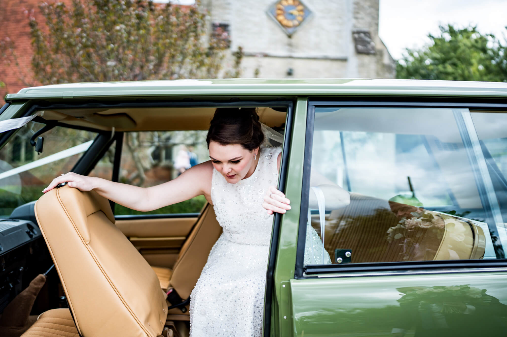 Bride stepping out green car.