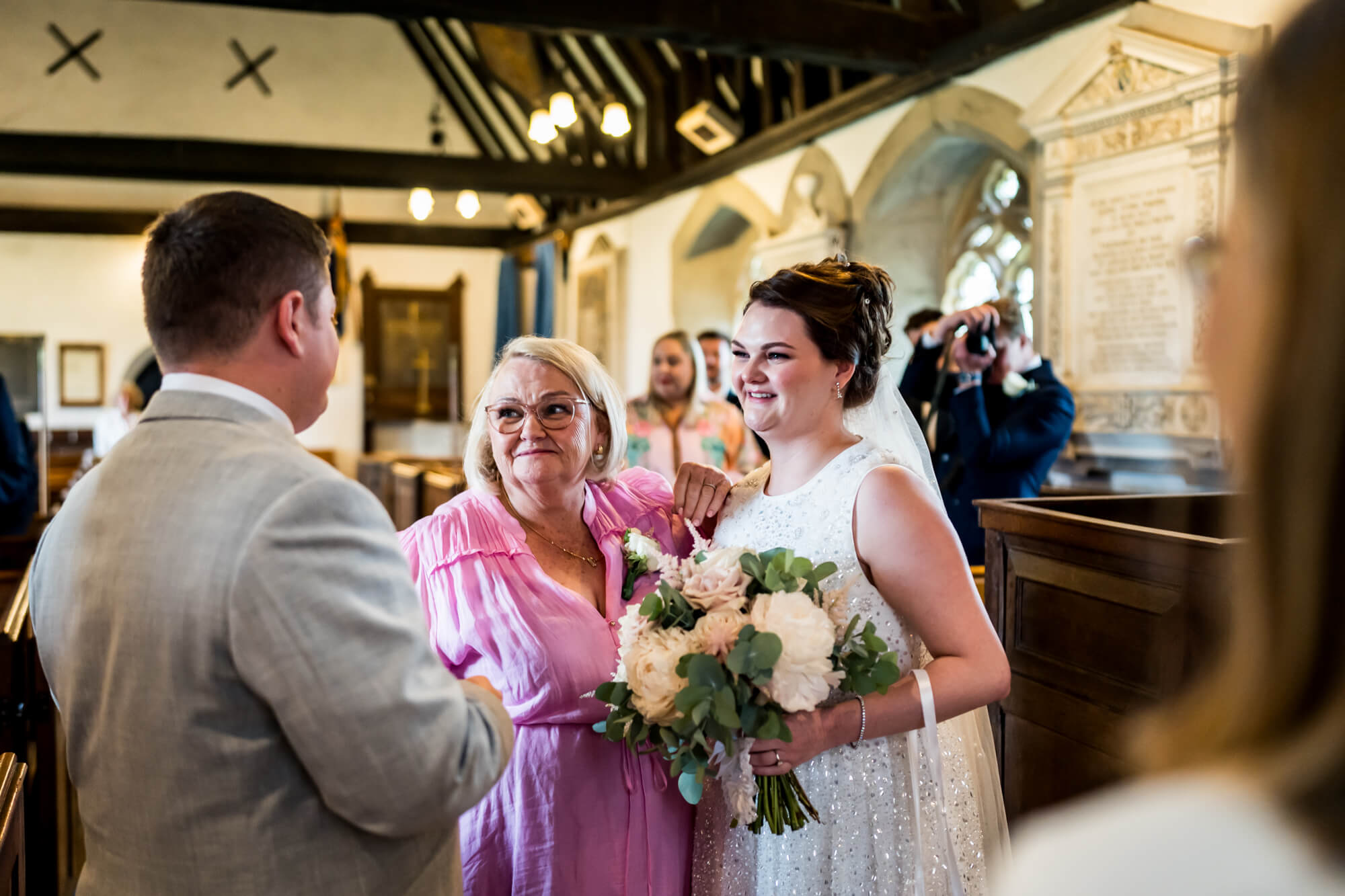 Groom interacting with bride and older woman.