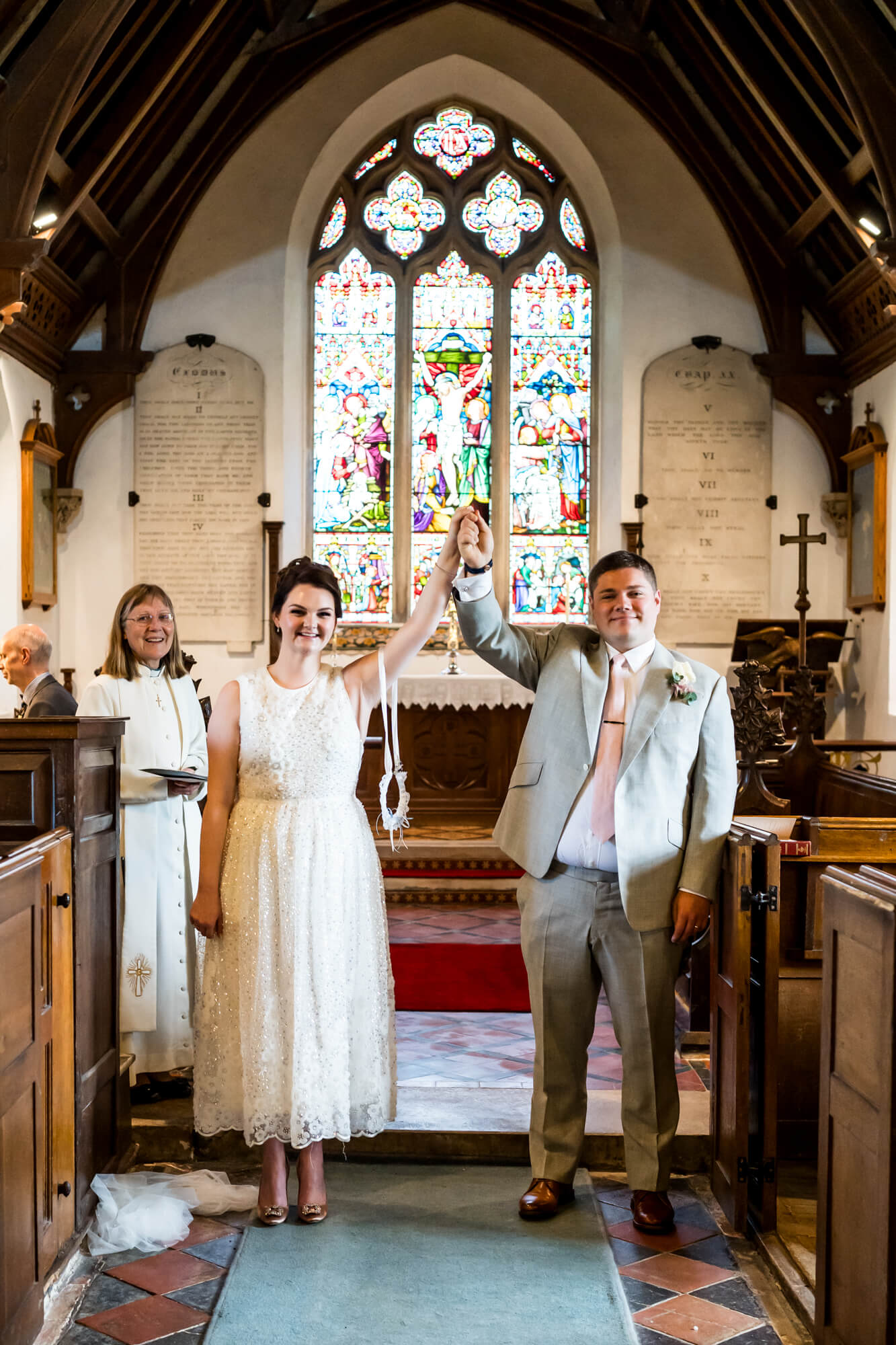 Bride and groom holding hands high in church.