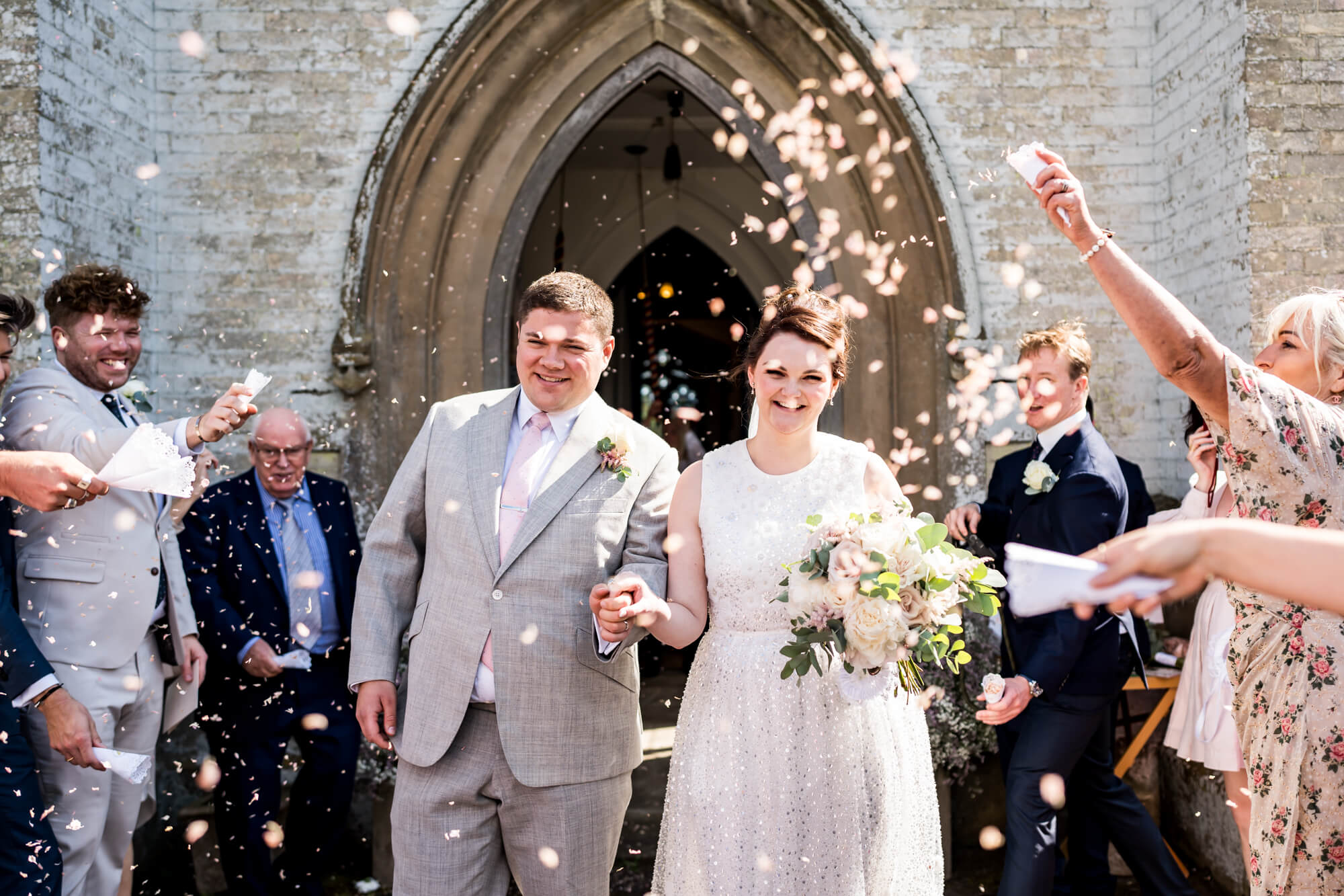 Bride and groom walking through celebratory crowd.