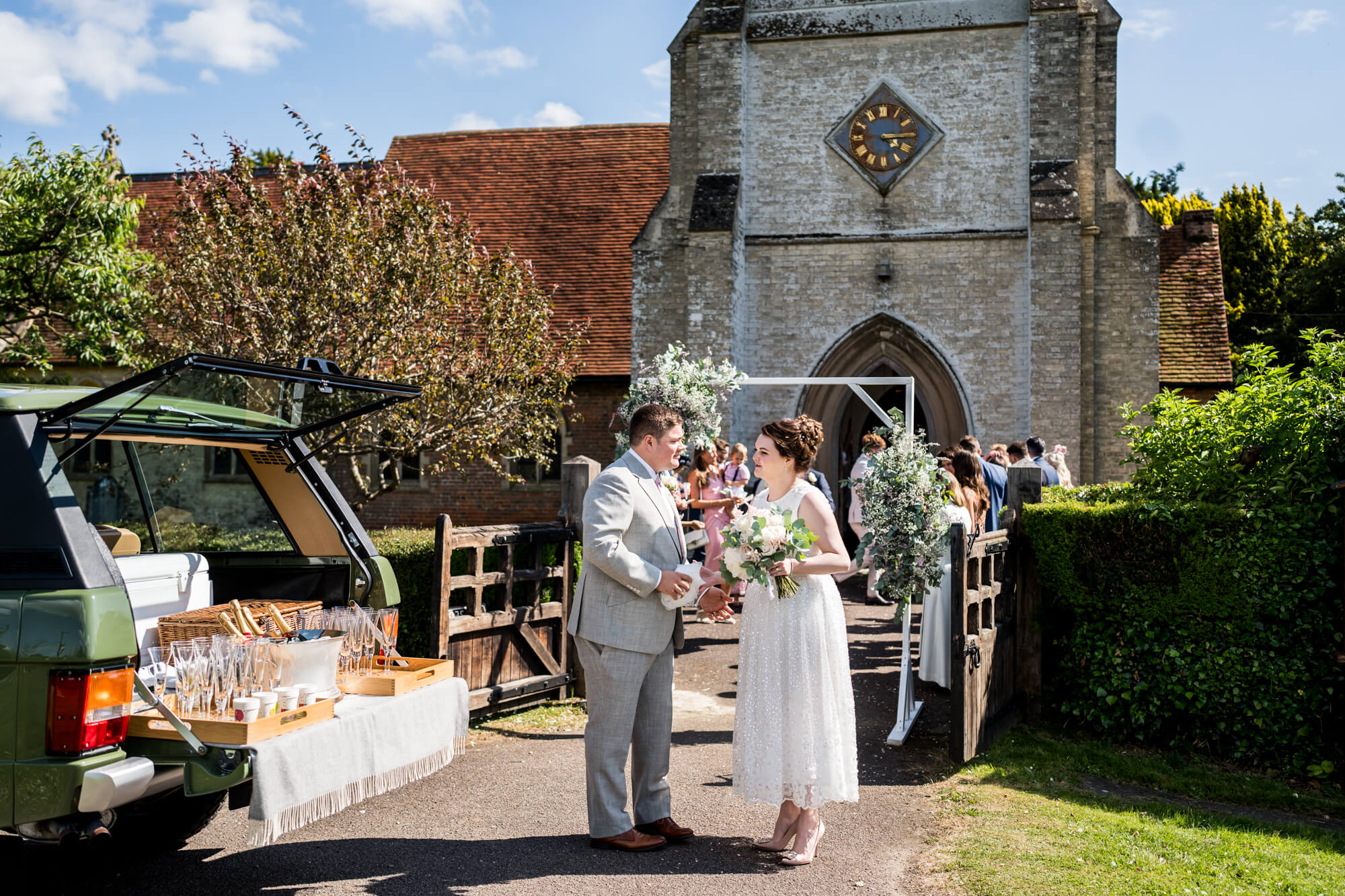 Bride and groom outside church with car.