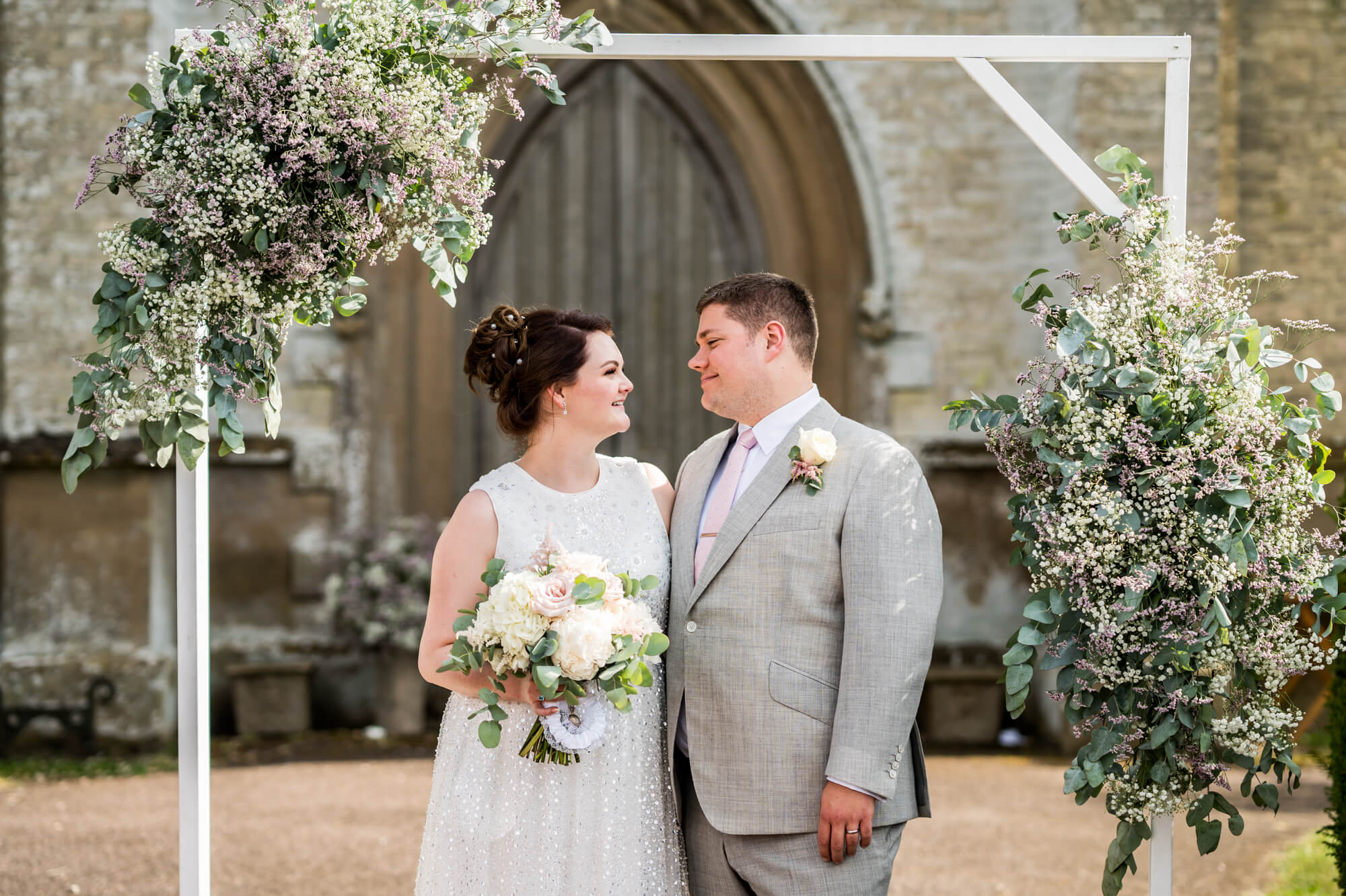 Bride and groom under flowered arch.