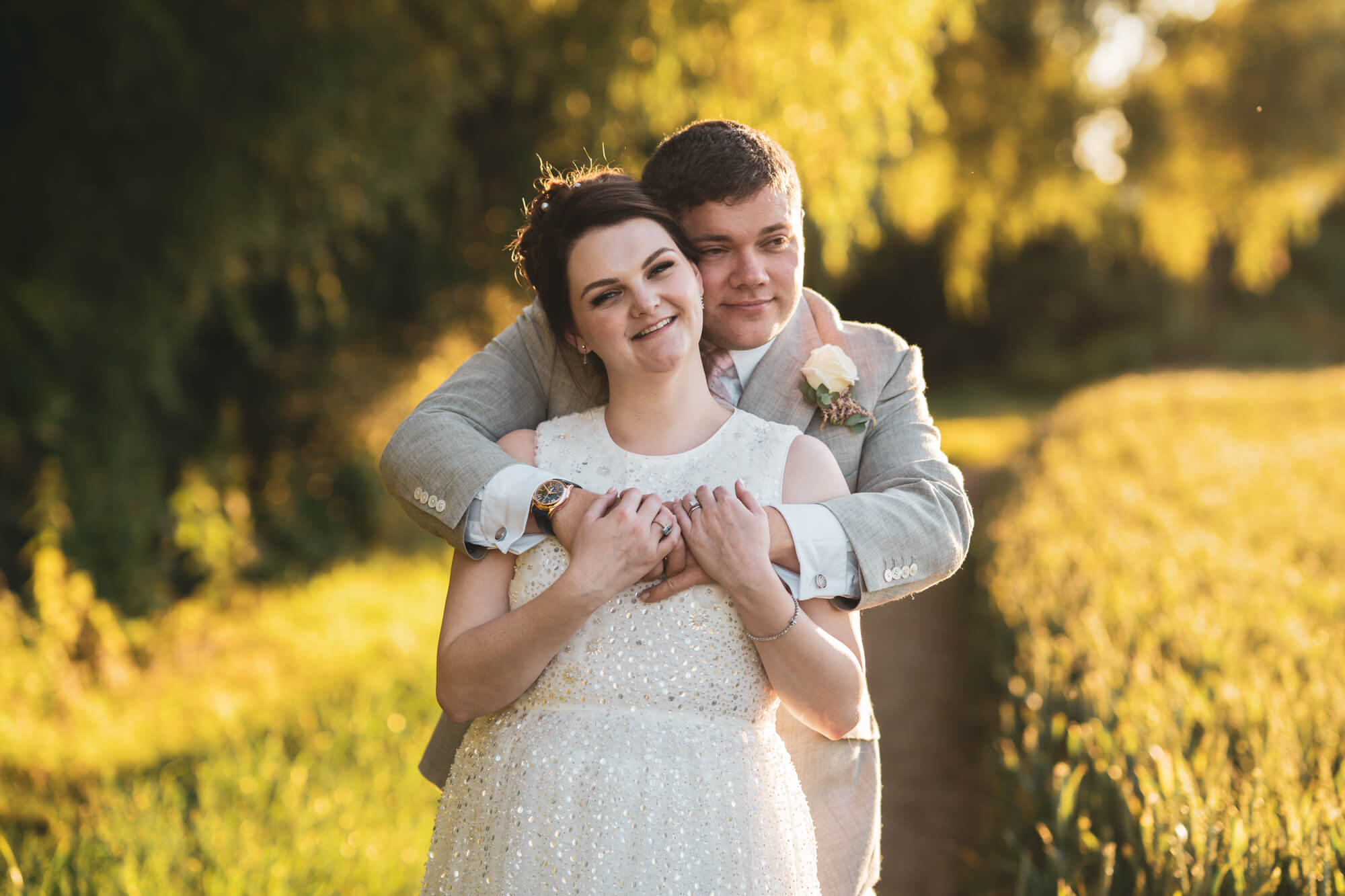 Groom hugging bride from behind.
