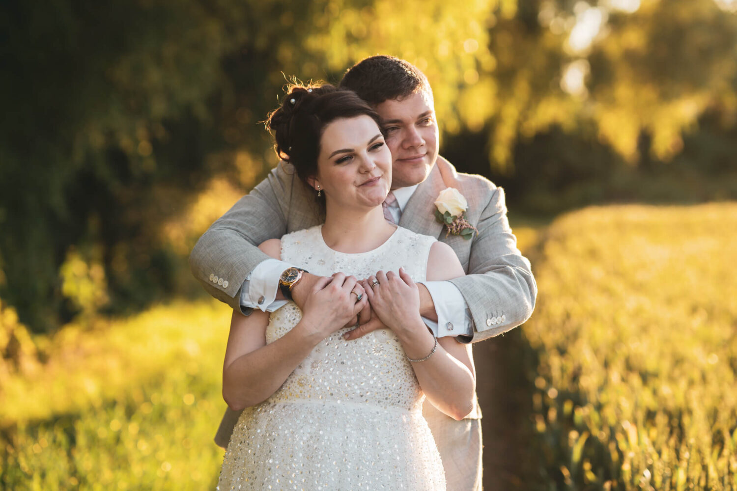 Groom hugging bride from behind.