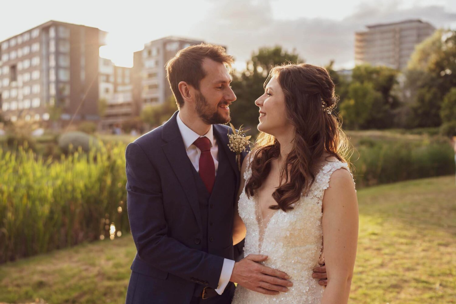 groom with hand on waist looking at bride golden hour london wedding