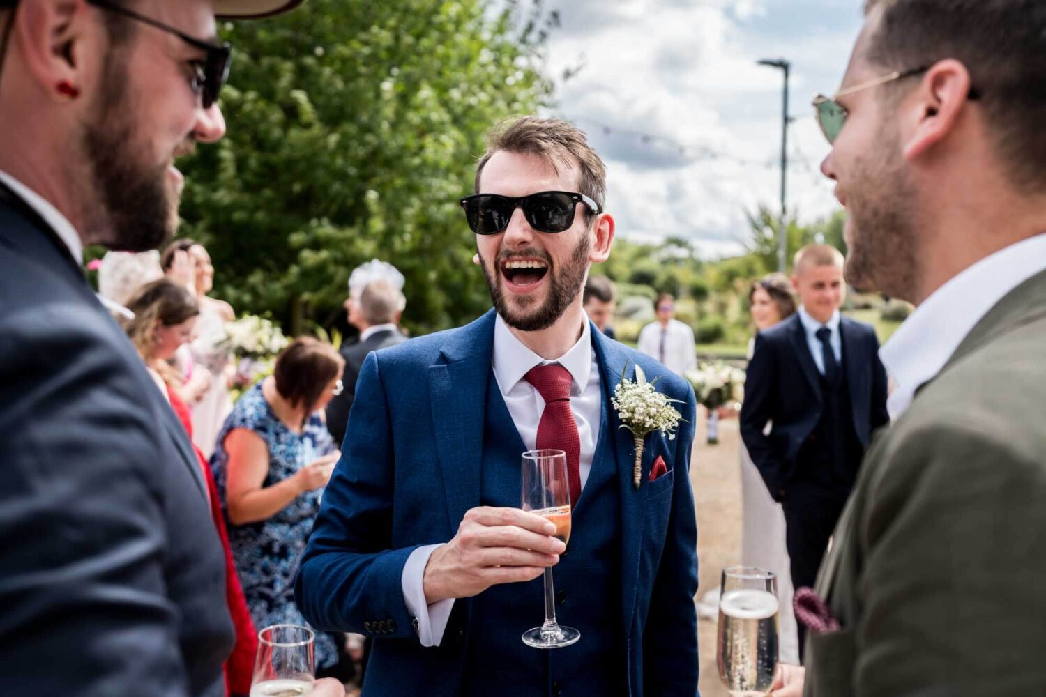 Groom laughing with drink in hand.