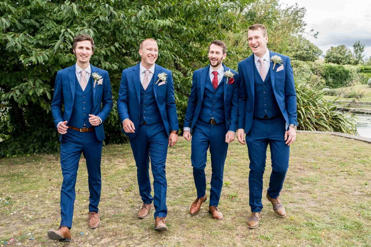 Groom and best men walking towards camera laughing.