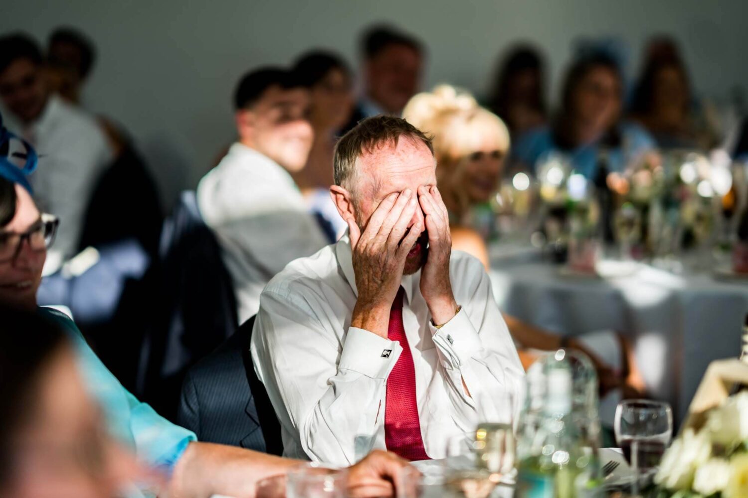Father of groom holding head in hands during speech.