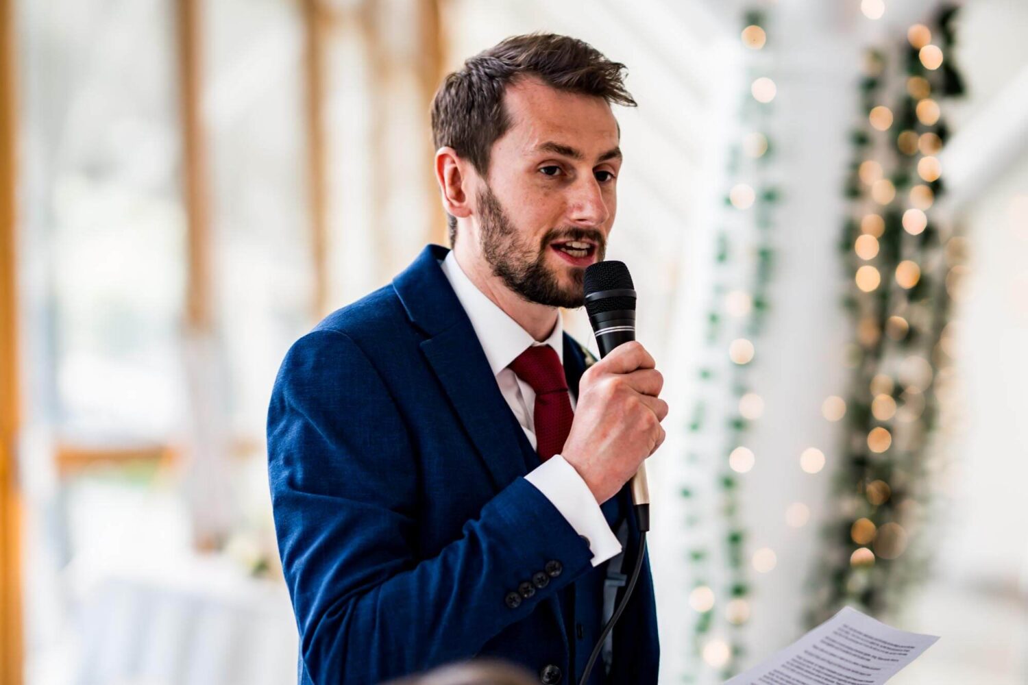 Groom speaking into microphone during his speech.