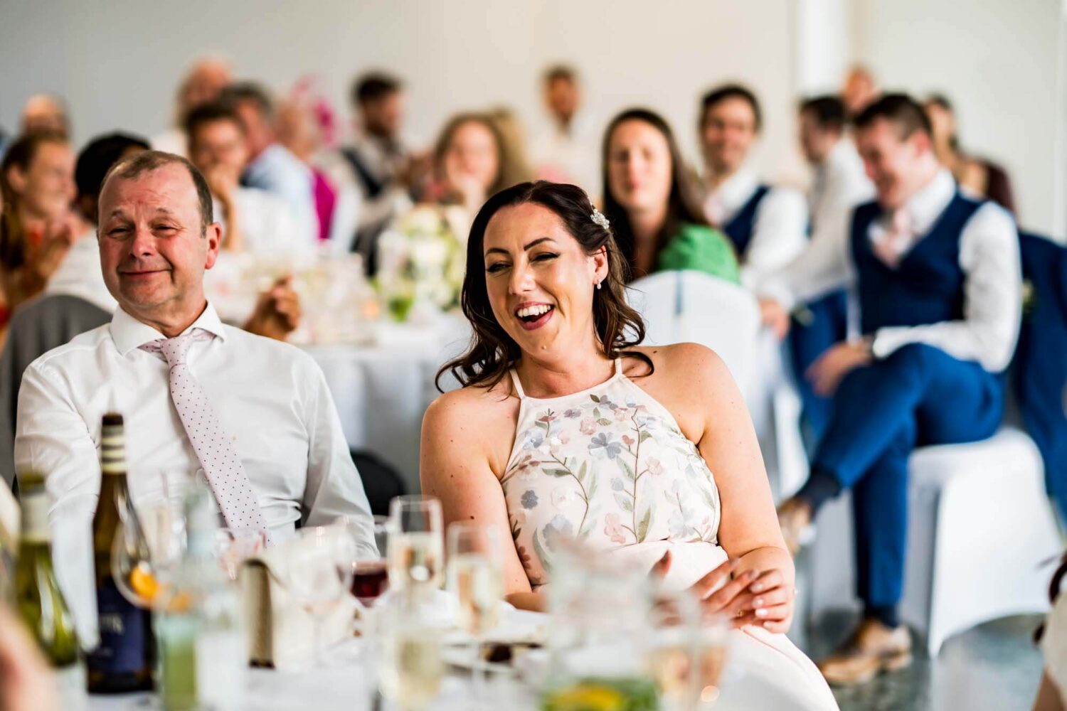 Sister of the bride sitting back laughing during the speeches.