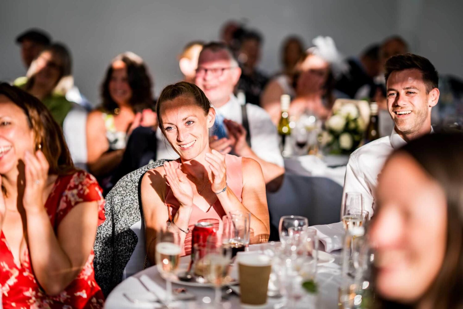 Guests with evening sunlight on face laughing during the speeches.