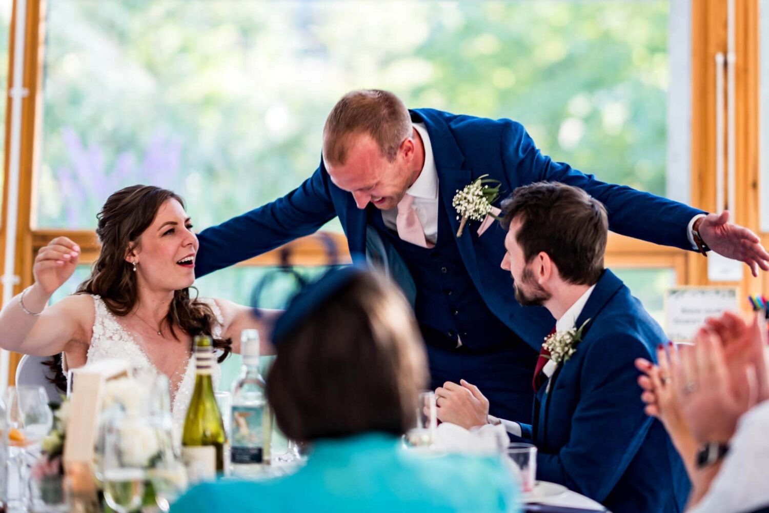 Best man leaning into bride and groom for a hug.