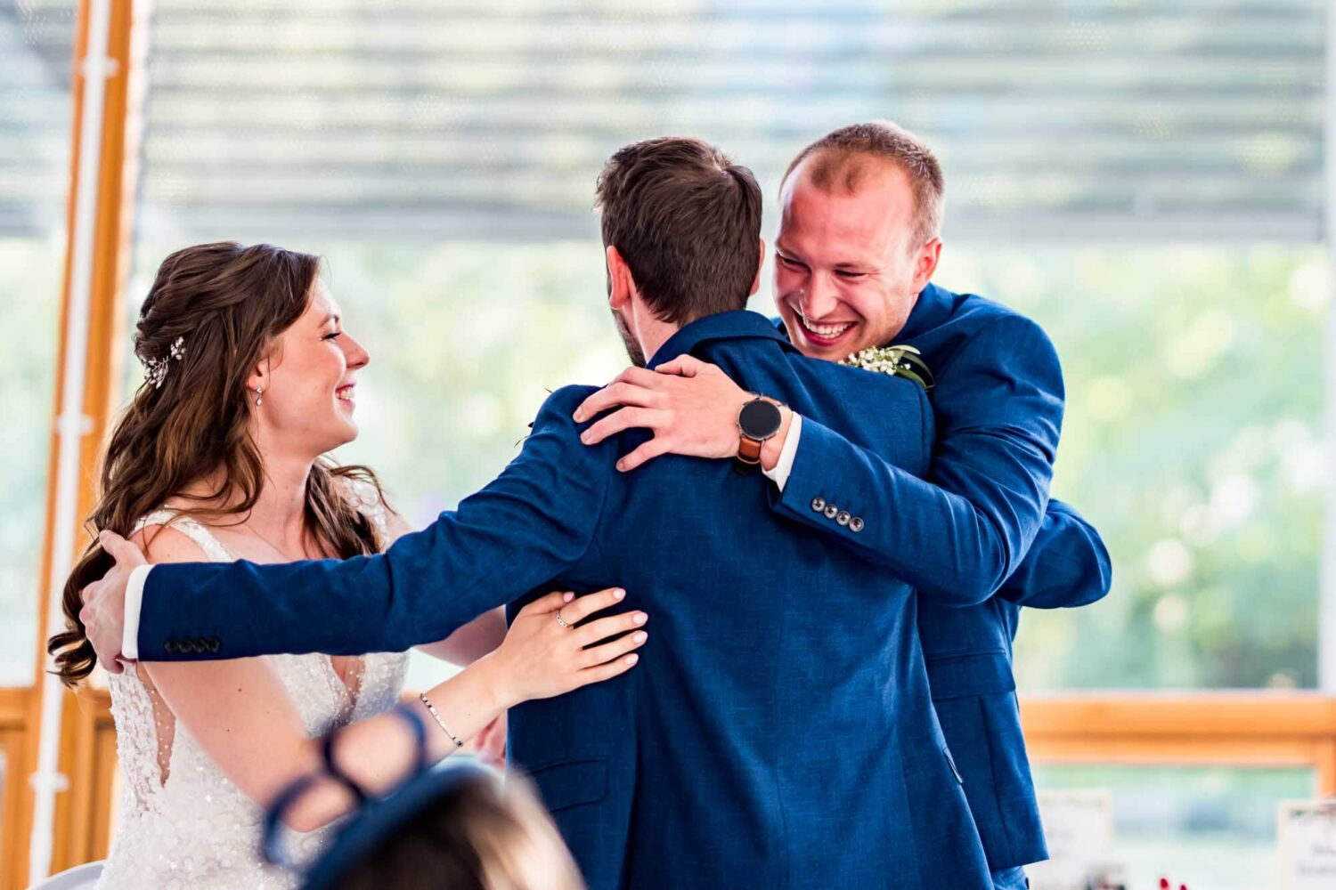 Best man and couple embracing for a hug during his speech.