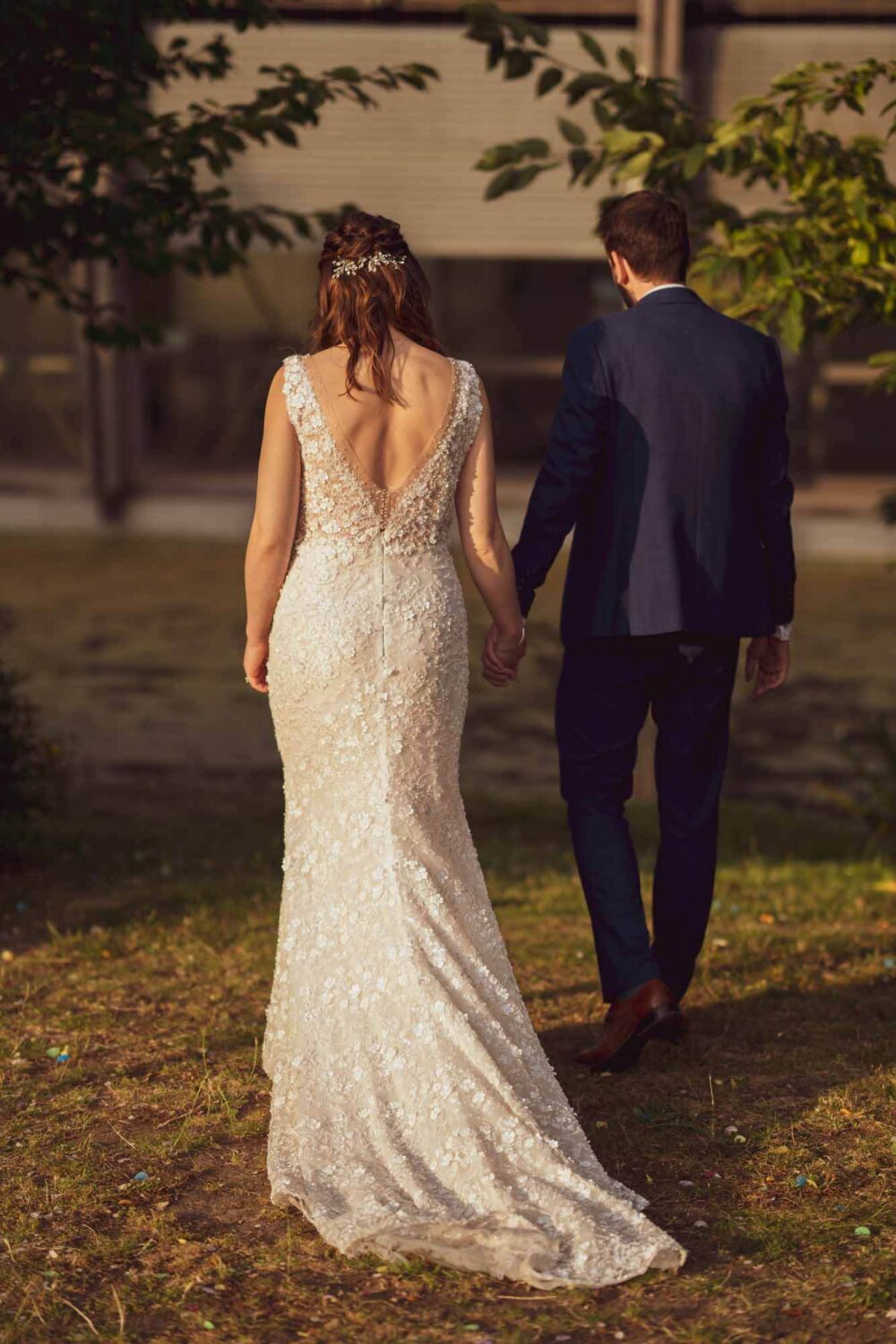 Bride and groom walking away from camera with sunlight on their backs.