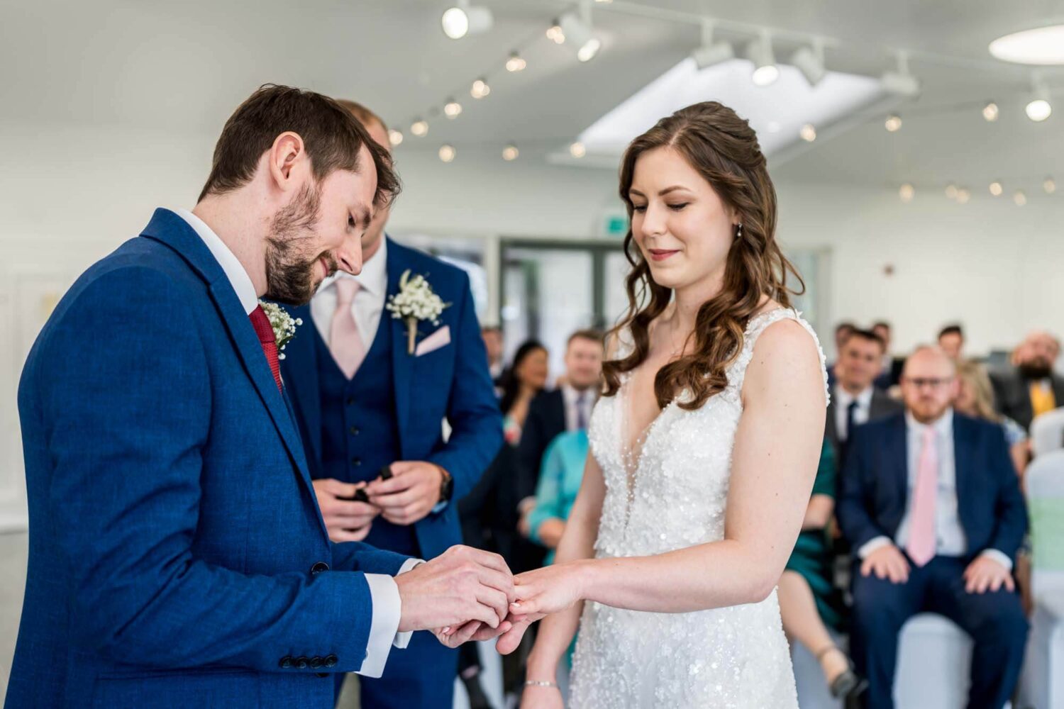Groom putting on ring on bride's fourth finger.