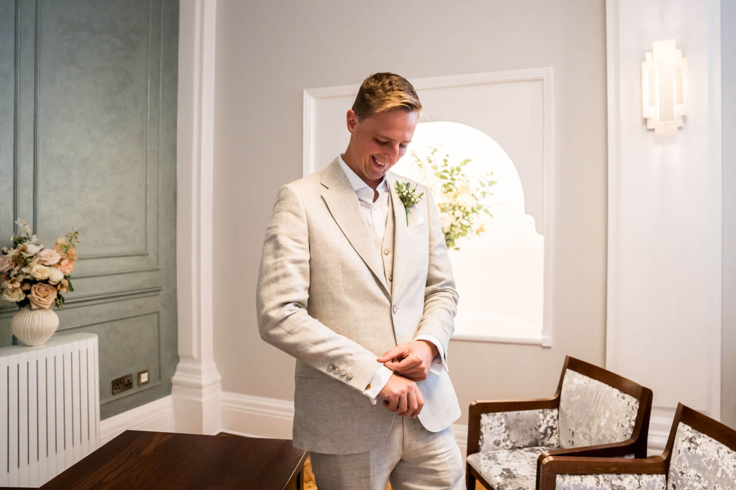 Groom looking down checking cufflinks Chelsea wedding.