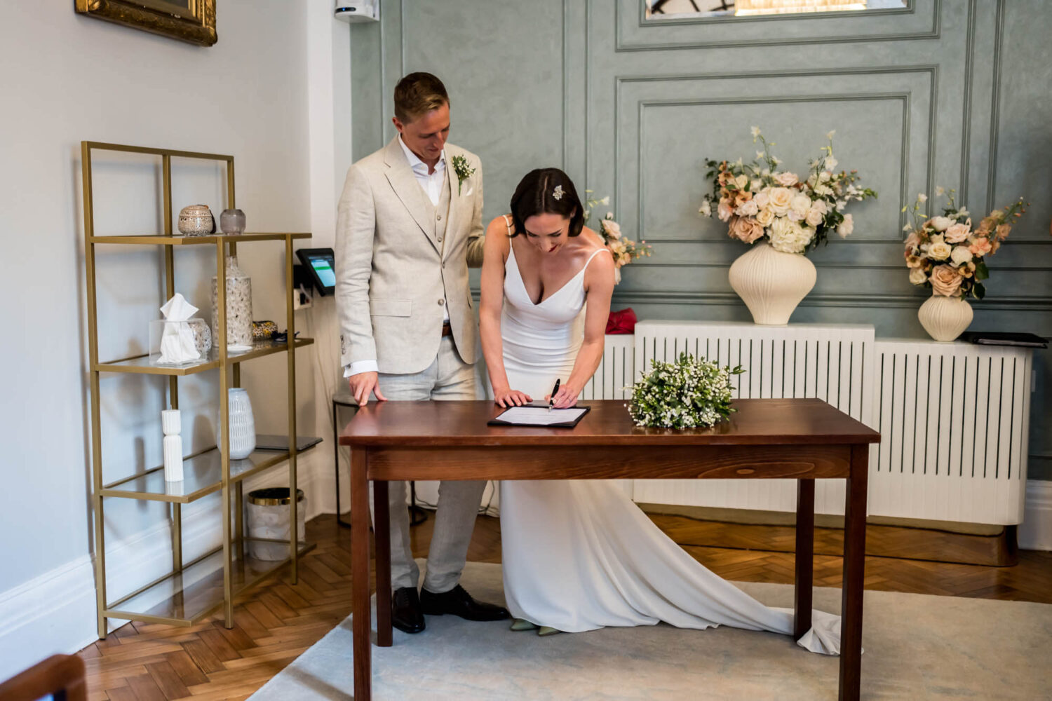 Bride signing register next to groom Chelsea wedding.