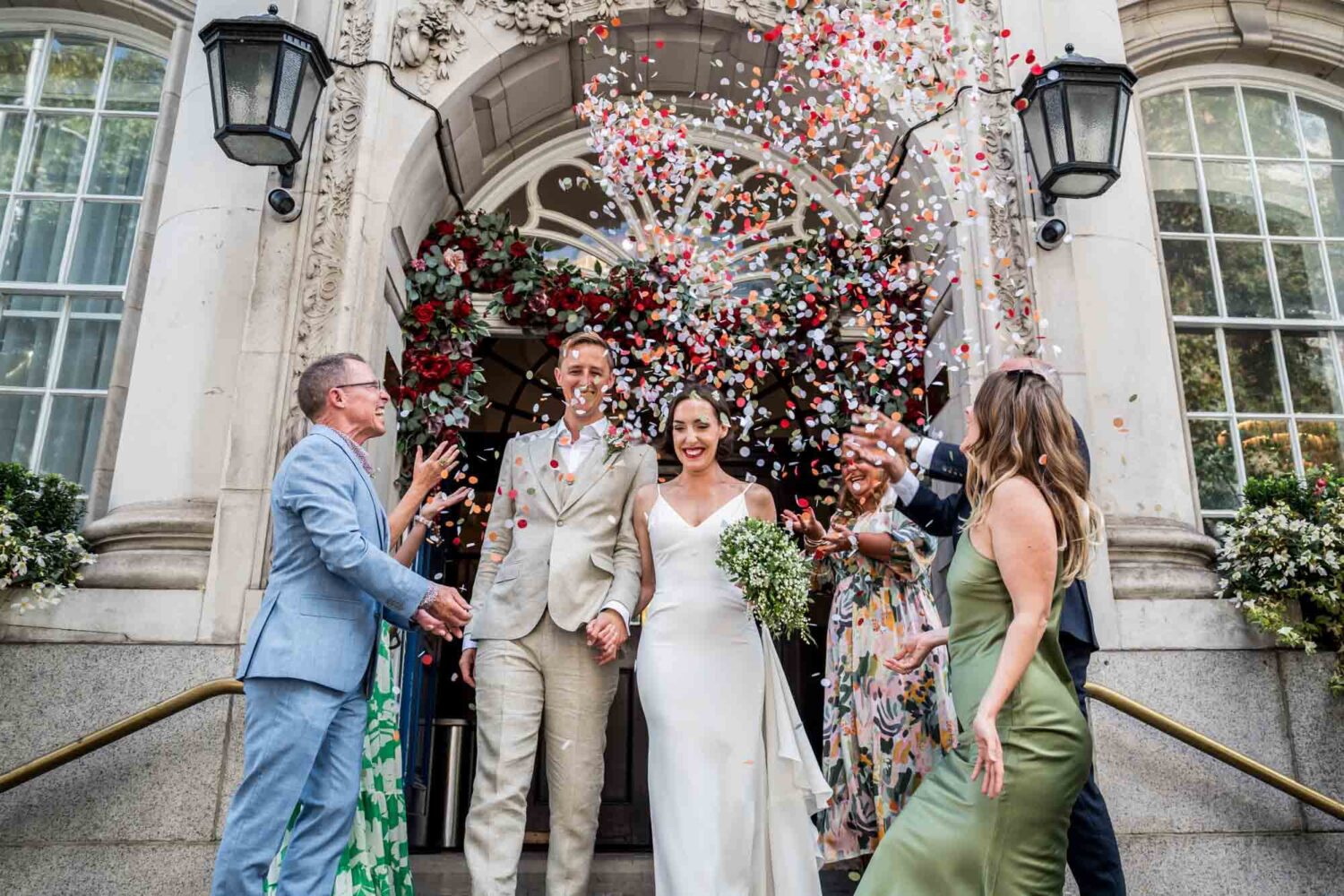 Bride and groom walking into shower of confetti Chelsea wedding.