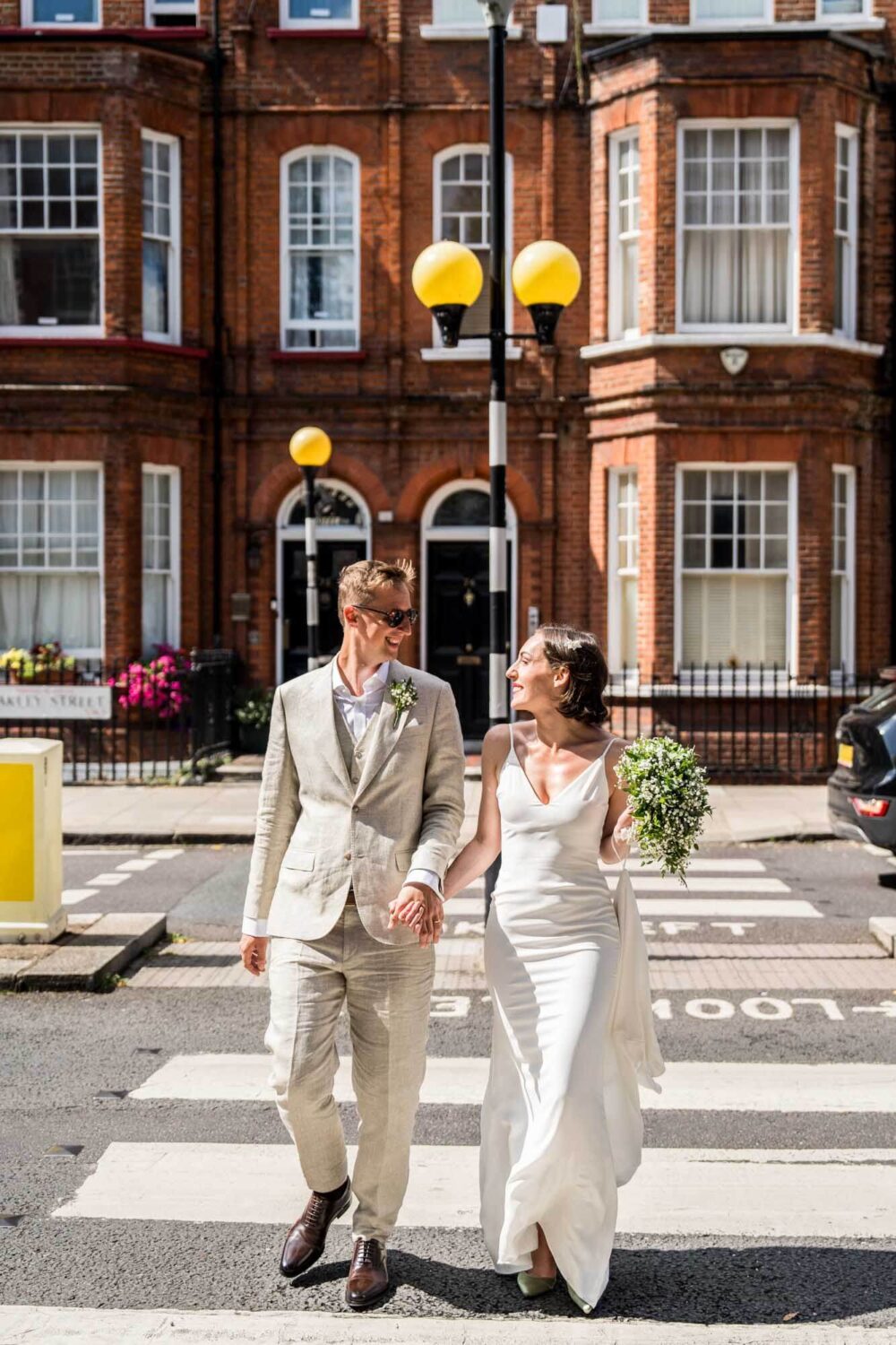 Bride and groom crossing pedestrian crossing Chelsea wedding.