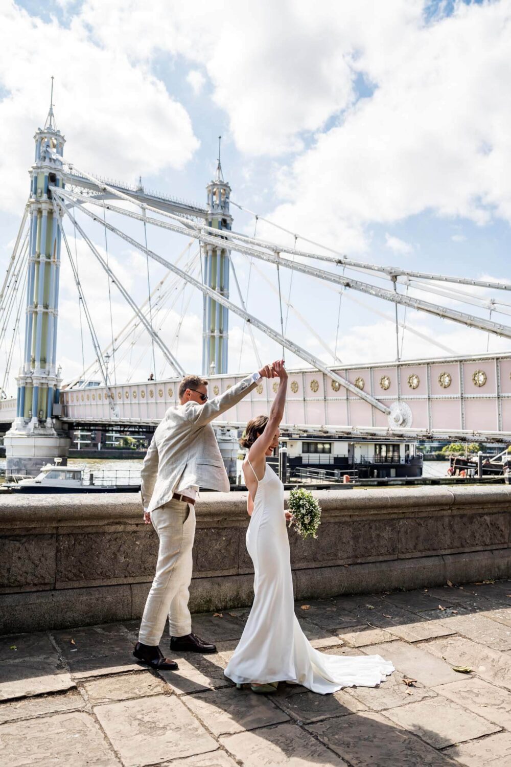 Groom giving bride a twirl by Thames Chelsea wedding.