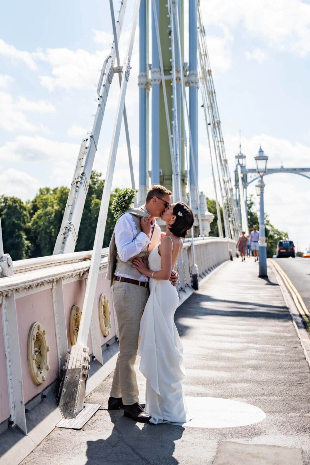 Bride and groom kissing on St Albert Bridge pavement Chelsea wedding.