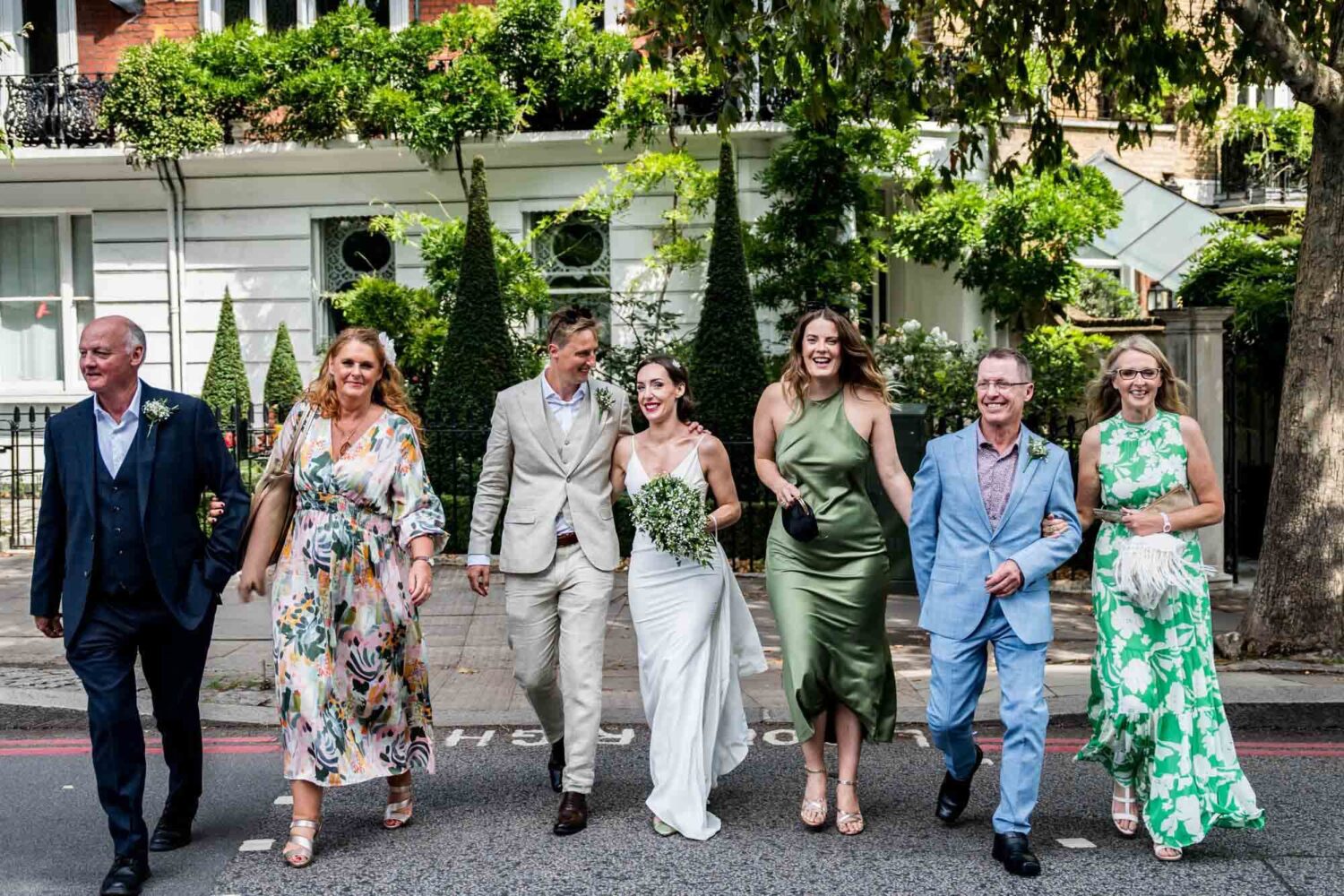 Wedding part all crossing the road together in a line Chelsea wedding.